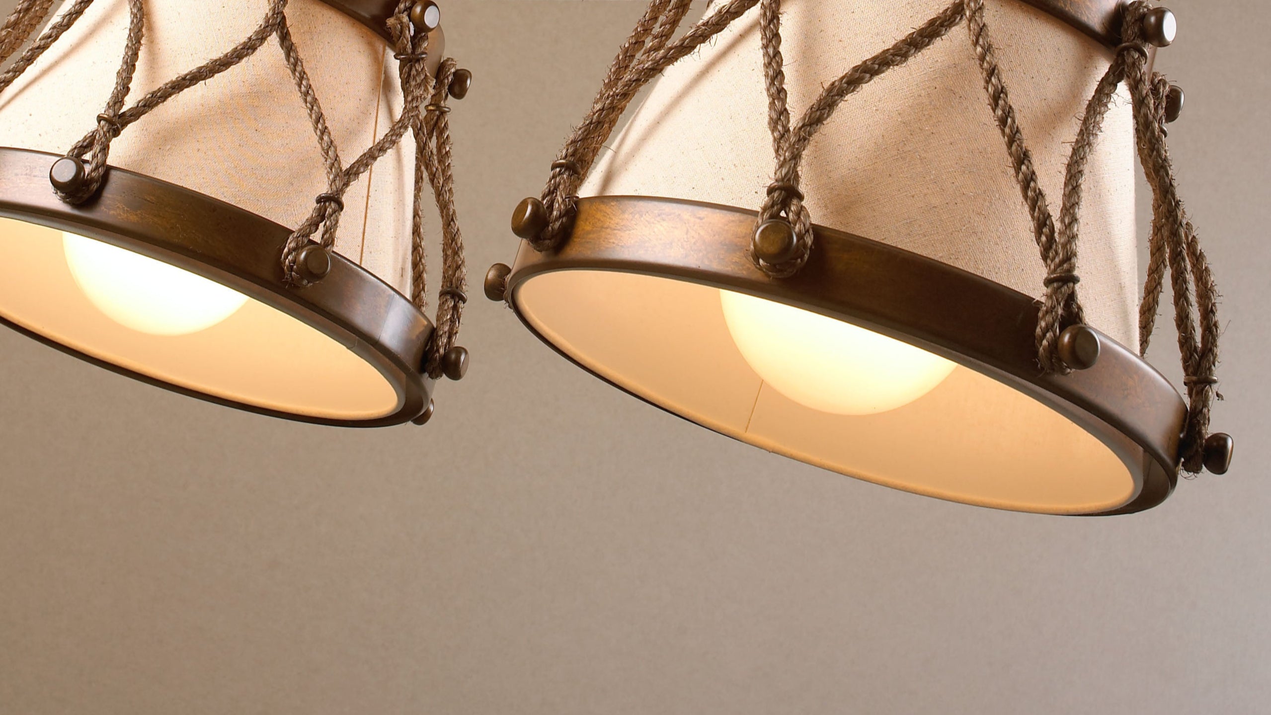 Detalhe de um candeeiro da Lustrarte que combina latão com acabamento terra, corda entrançada e abat-jour em tecido algodão rústico.