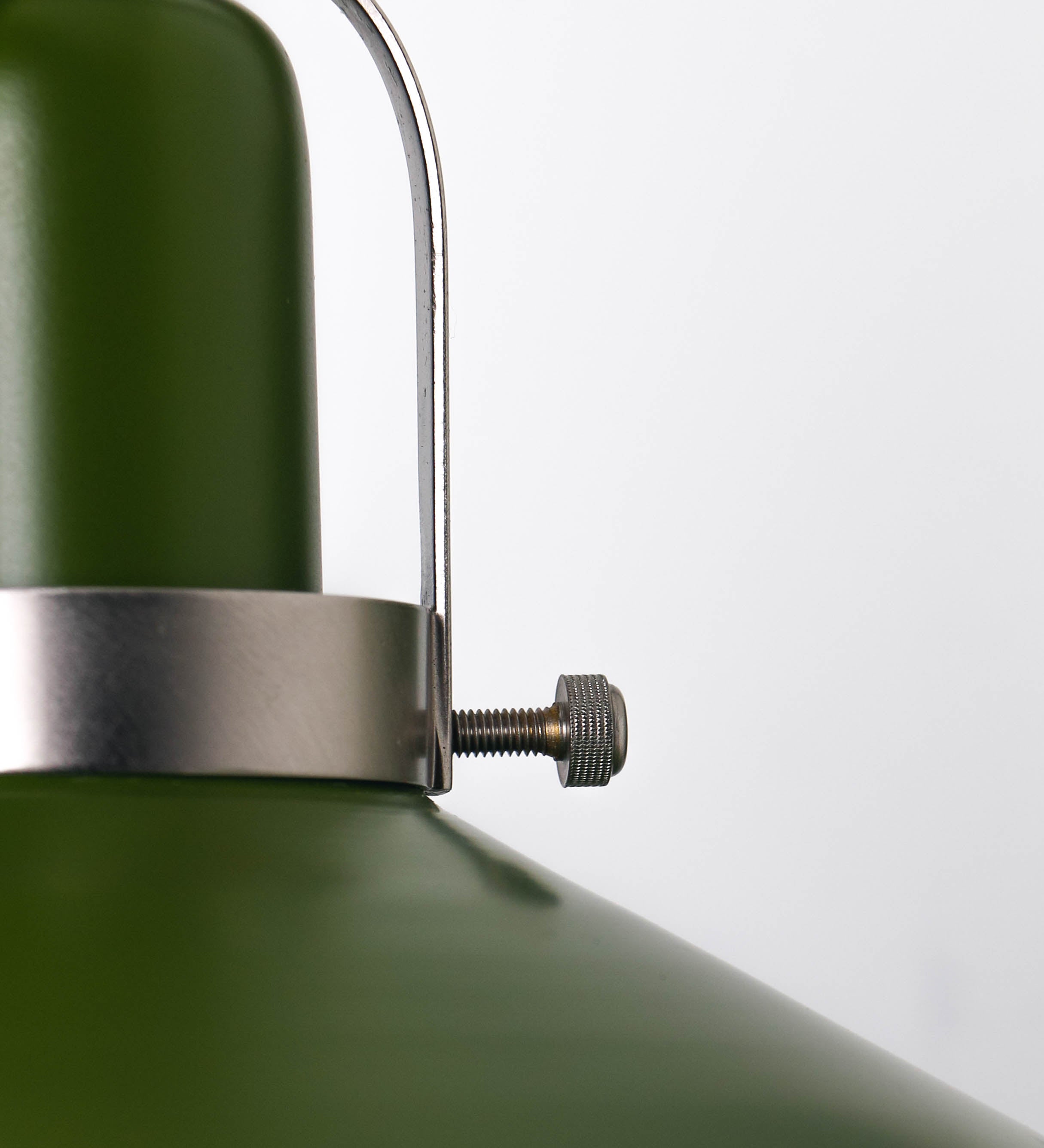 Aplique de parede com um design clássico e cores contemporâneas. O aplique é composto por uma base circular verde couve-de-bruxelas, de onde se estende um braço curvo, que forma um arco gracioso e sustenta o chapéu do candeeiro, verde também. O chapéu tem um formato cónico invertido, com uma borda ligeiramente levantada, que direciona a luz para baixo. O interior do chapéu é branco. No topo do chapéu, há um suporte circular em níquel escovado, com três braços que fixa o chapéu ao braço curvo.