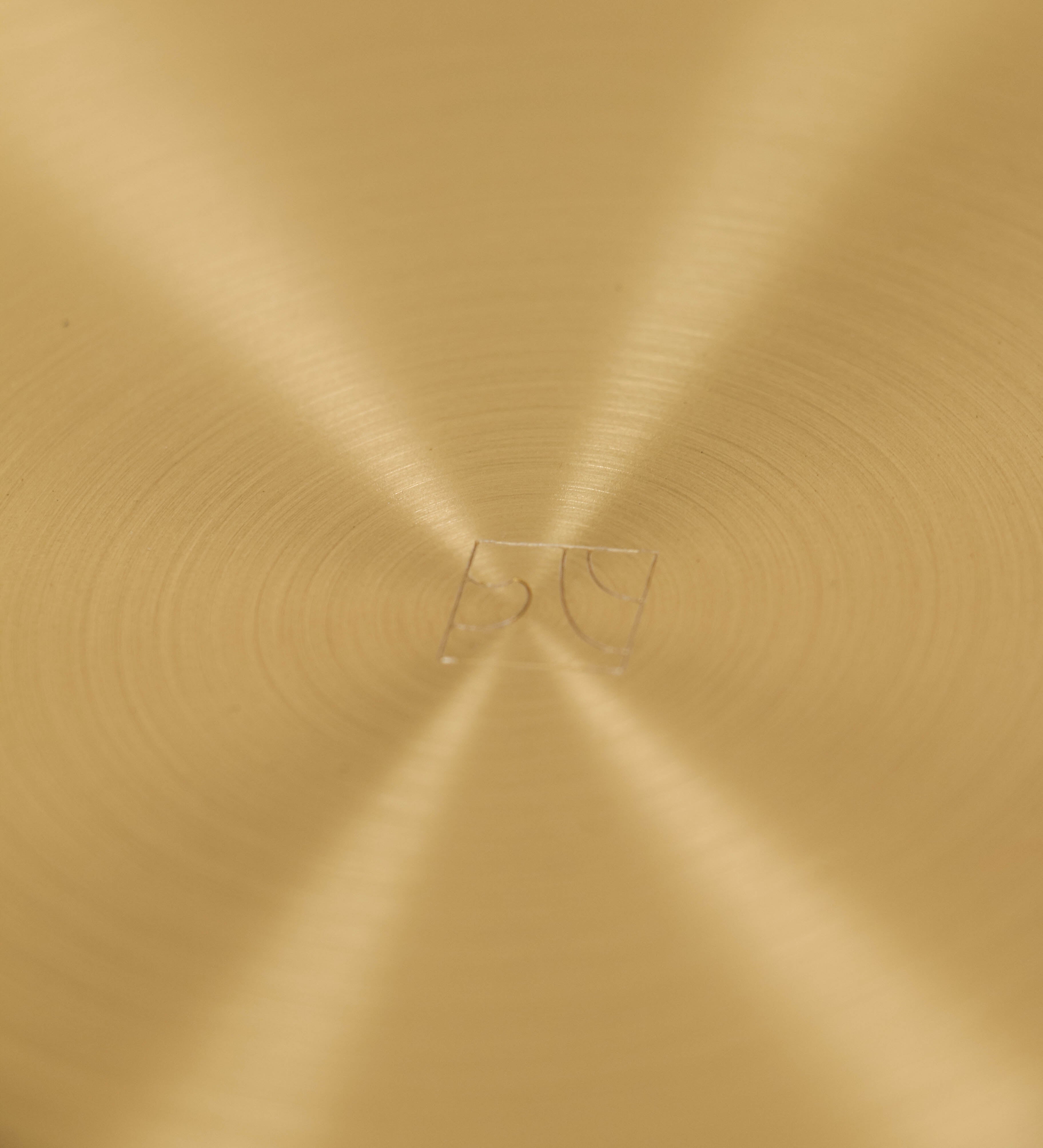 Bandeja com um design sofisticado e intemporal. A bandeja é de latão, com um tom dourado mate e acabamento escovado. Tem uma forma circular, de superfície plana e com uma borda envolvente de altura média e grossura fina. Na sua base tem três pequenas esferas, em latão também, dispostas em formato triangular, que sustentam o prato circular no topo.