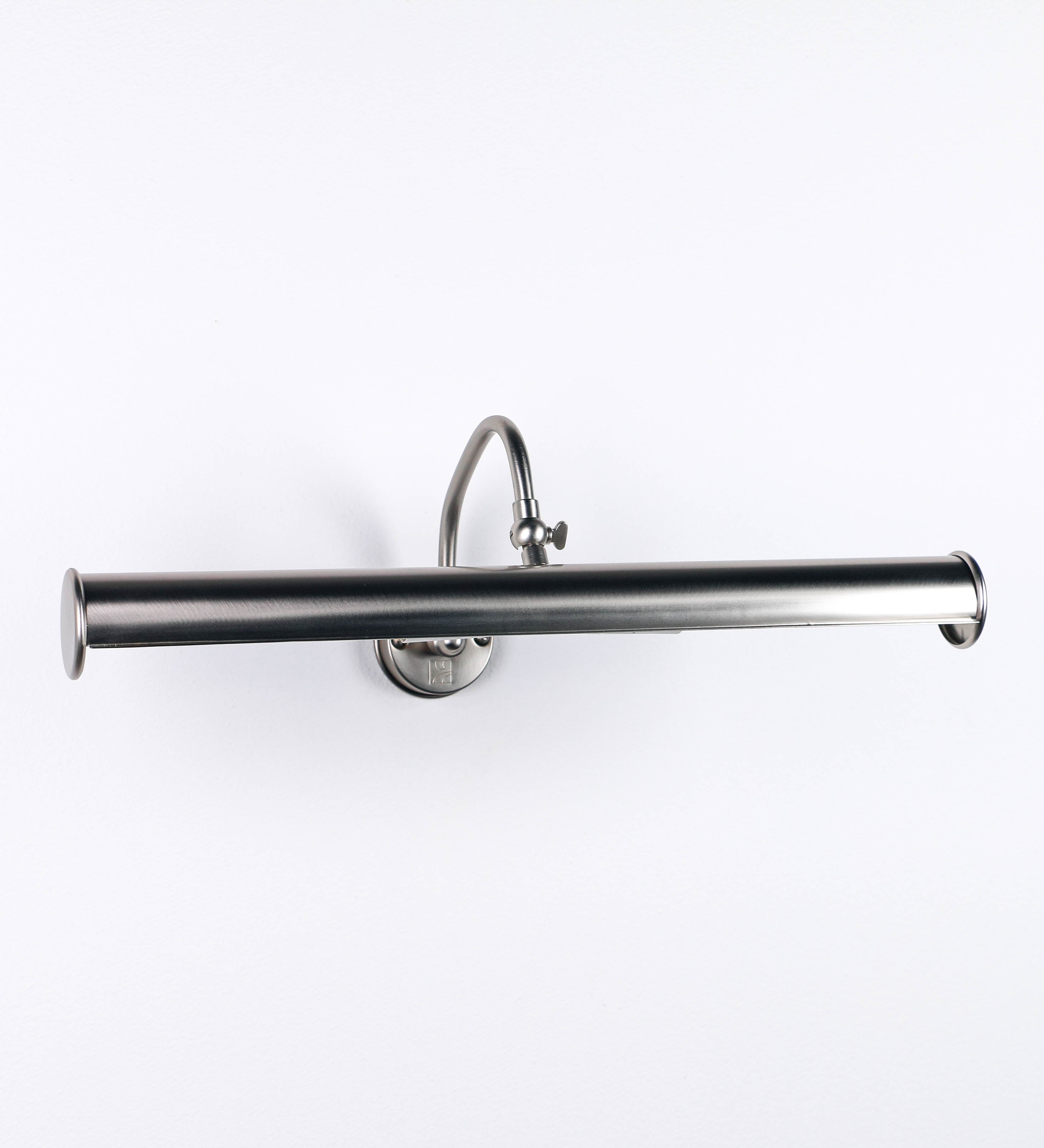Aplique de parede que combina elementos clássicos com toques contemporâneos, todo em níquel escovado. O aplique é composto por uma base circular de onde se estende um braço curvo e gracioso, que suporta a barra principal. O braço contém um elemento que permite apertar ou desapertar a barra para melhor manipular a direção da luz. A barra de 45cm de largura é cilíndrica e alongada. As extremidades do cilindro são planas e do mesmo diâmetro.
