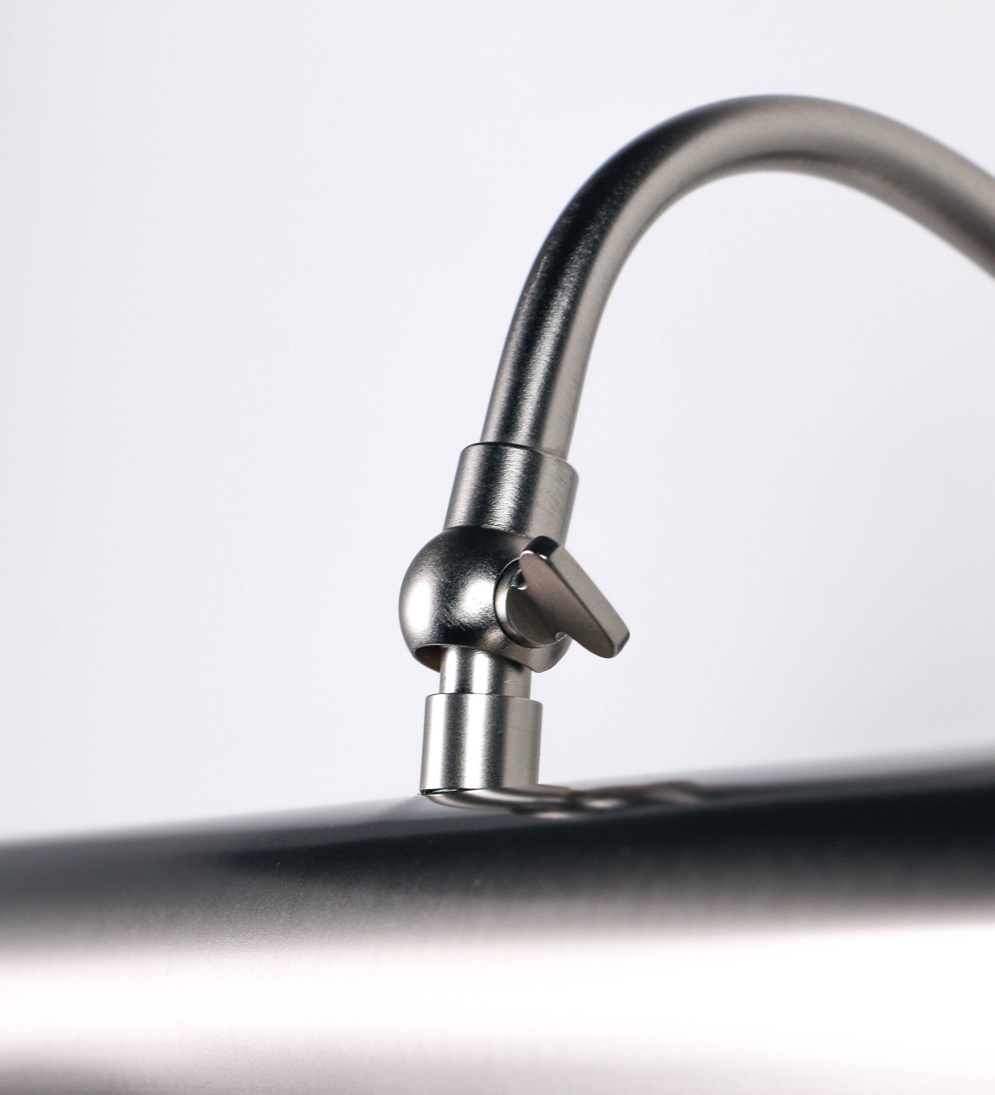 Aplique de parede que combina elementos clássicos com toques contemporâneos, todo em níquel escovado. O aplique é composto por uma base circular de onde se estende um braço curvo e gracioso, que suporta a barra principal. O braço contém um elemento que permite apertar ou desapertar a barra para melhor manipular a direção da luz. A barra de 45cm de largura é cilíndrica e alongada. As extremidades do cilindro são planas e do mesmo diâmetro.