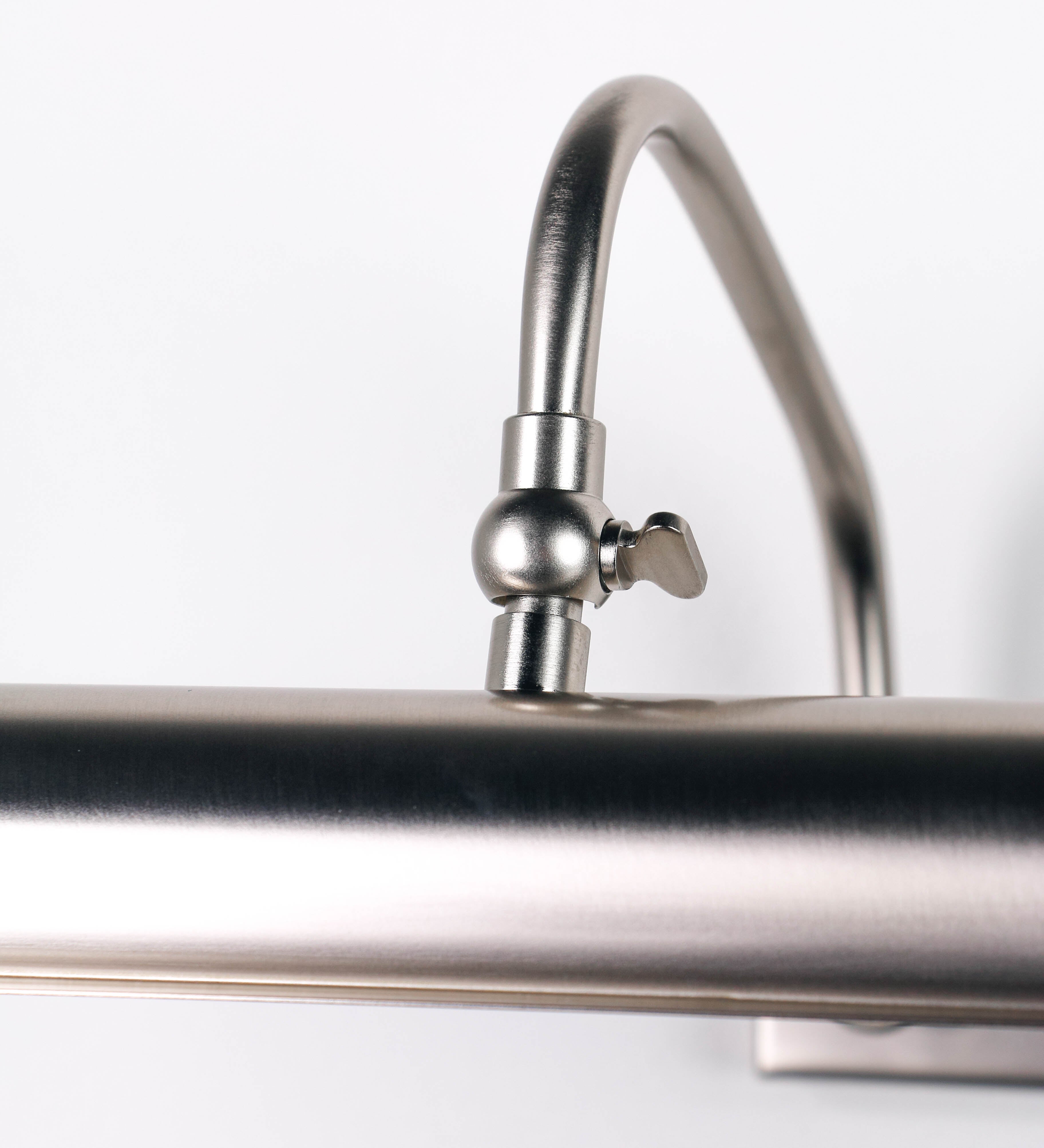 Aplique de parede que combina elementos clássicos com toques contemporâneos, todo em níquel escovado. O aplique é composto por uma base retangular, de onde se estendem dois braços curvos e graciosos, que suportam a barra principal. Os braços contêm um elemento que permite apertar ou desapertar a barra para melhor manipular a direção da luz. A barra de 65cm de largura é cilíndrica e alongada. As extremidades do cilindro são planas e do mesmo diâmetro.
