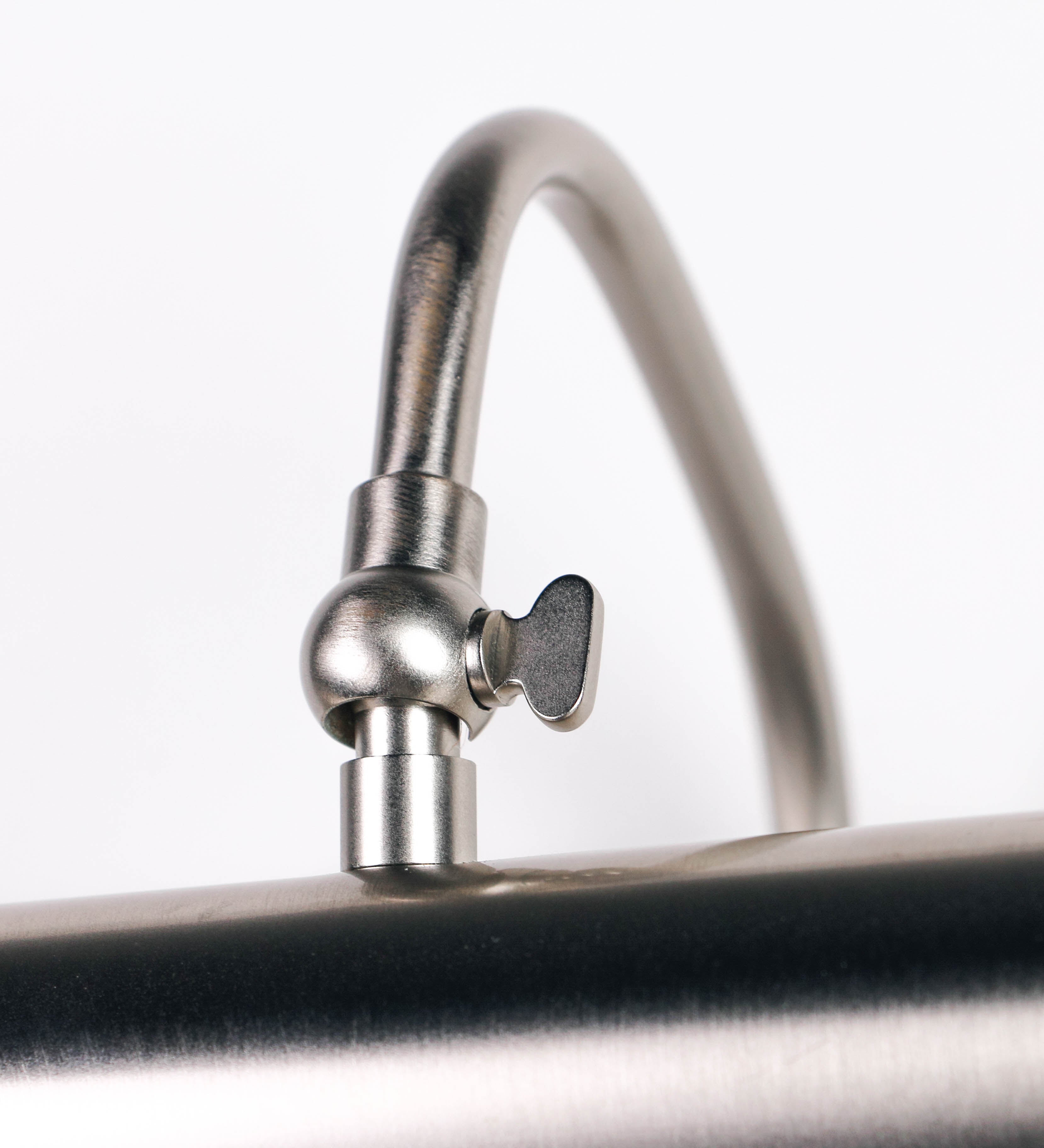 Aplique de parede que combina elementos clássicos com toques contemporâneos, todo em níquel escovado. O aplique é composto por uma base circular de onde se estende um braço curvo e gracioso, que suporta a barra principal. O braço contém um elemento que permite apertar ou desapertar a barra para melhor manipular a direção da luz. A barra de 25cm de largura é cilíndrica e alongada. As extremidades do cilindro são planas e do mesmo diâmetro.