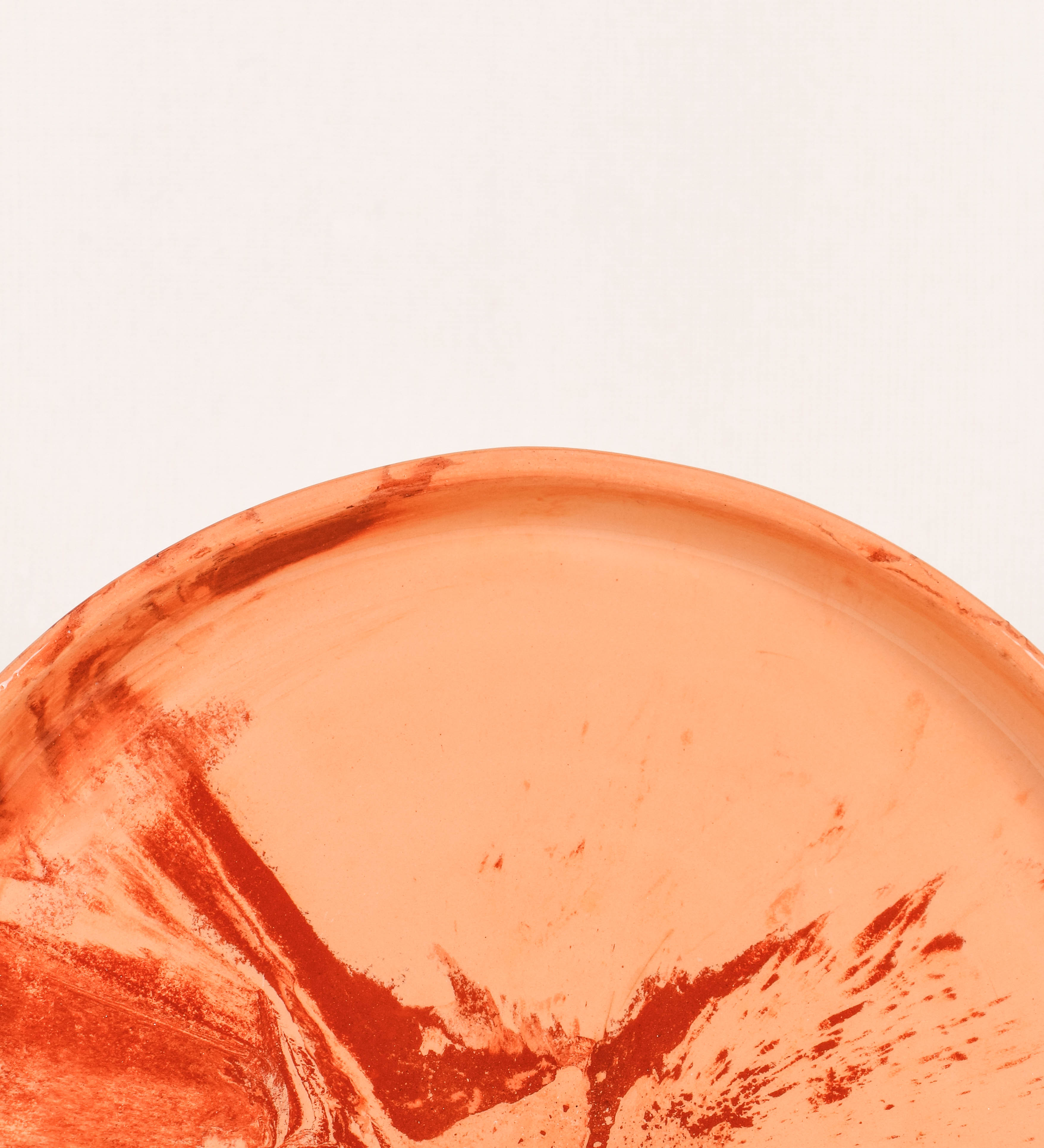 Prato raso com design minimalista e distinto. O prato é de barro, com uma mistura dois tipos de barro diferentes, um mais escuro e outro mais claro. Esta mistura cria um desenho de formas abstratas e aleatórias, que se espalham por todas as superfícies do prato. Tem um acabamento vidrado transparente com brilho, conferindo um toque de sofisticação e preservando os tons naturais dos barros. A forma do prato é circular, com uma borda envolvente de altura baixa e design simples e minimalista.