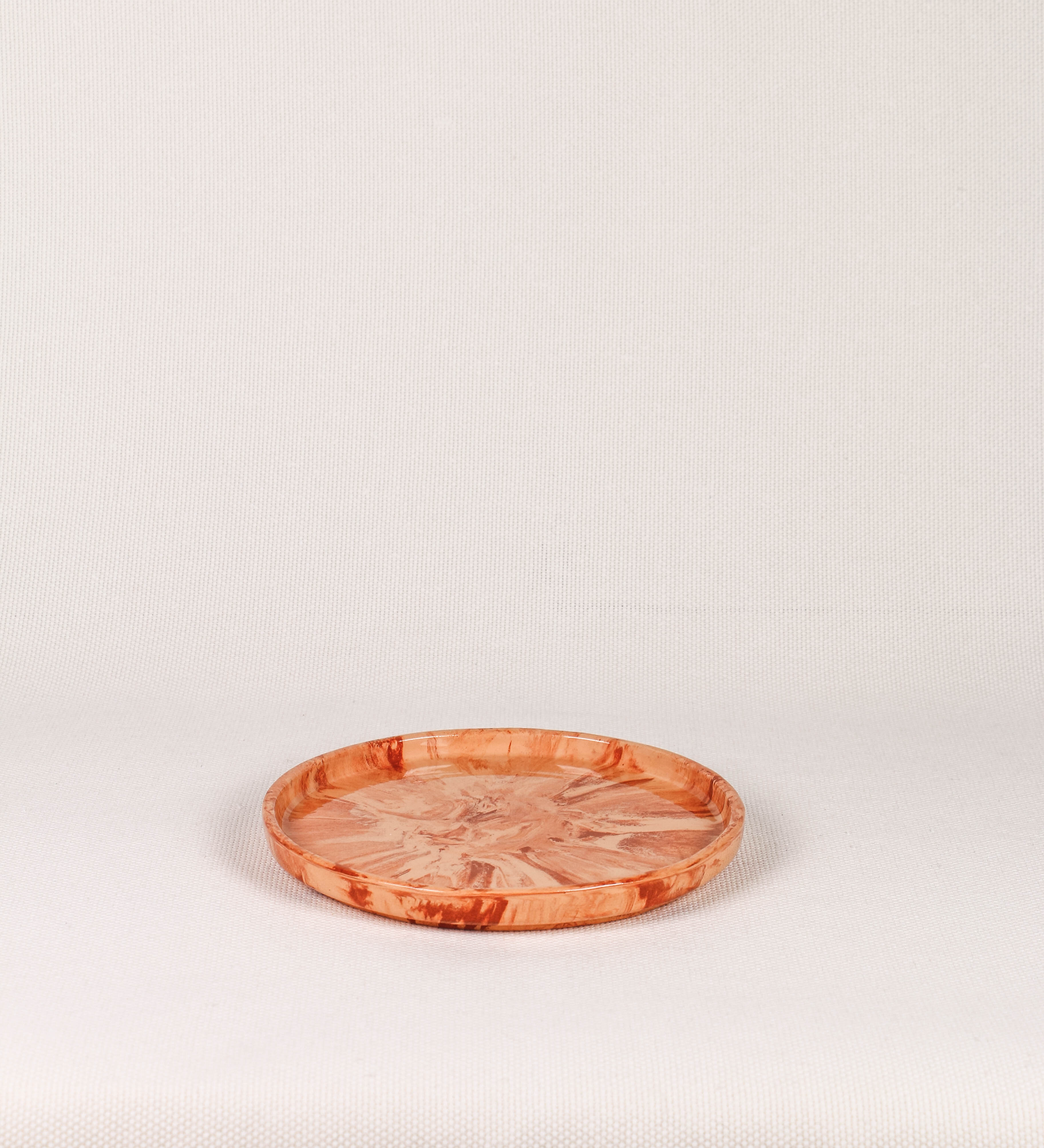 Prato de aperitivos com design minimalista e distinto. O prato é de barro, com uma mistura dois tipos de barro diferentes, um mais escuro e outro mais claro. Esta mistura cria um desenho de formas abstratas e aleatórias, que se espalham por todas as superfícies do prato. Tem um acabamento vidrado transparente com brilho, conferindo um toque de sofisticação e preservando os tons naturais dos barros. A forma do prato é circular, com uma borda envolvente de altura baixa e design simples e minimalista.