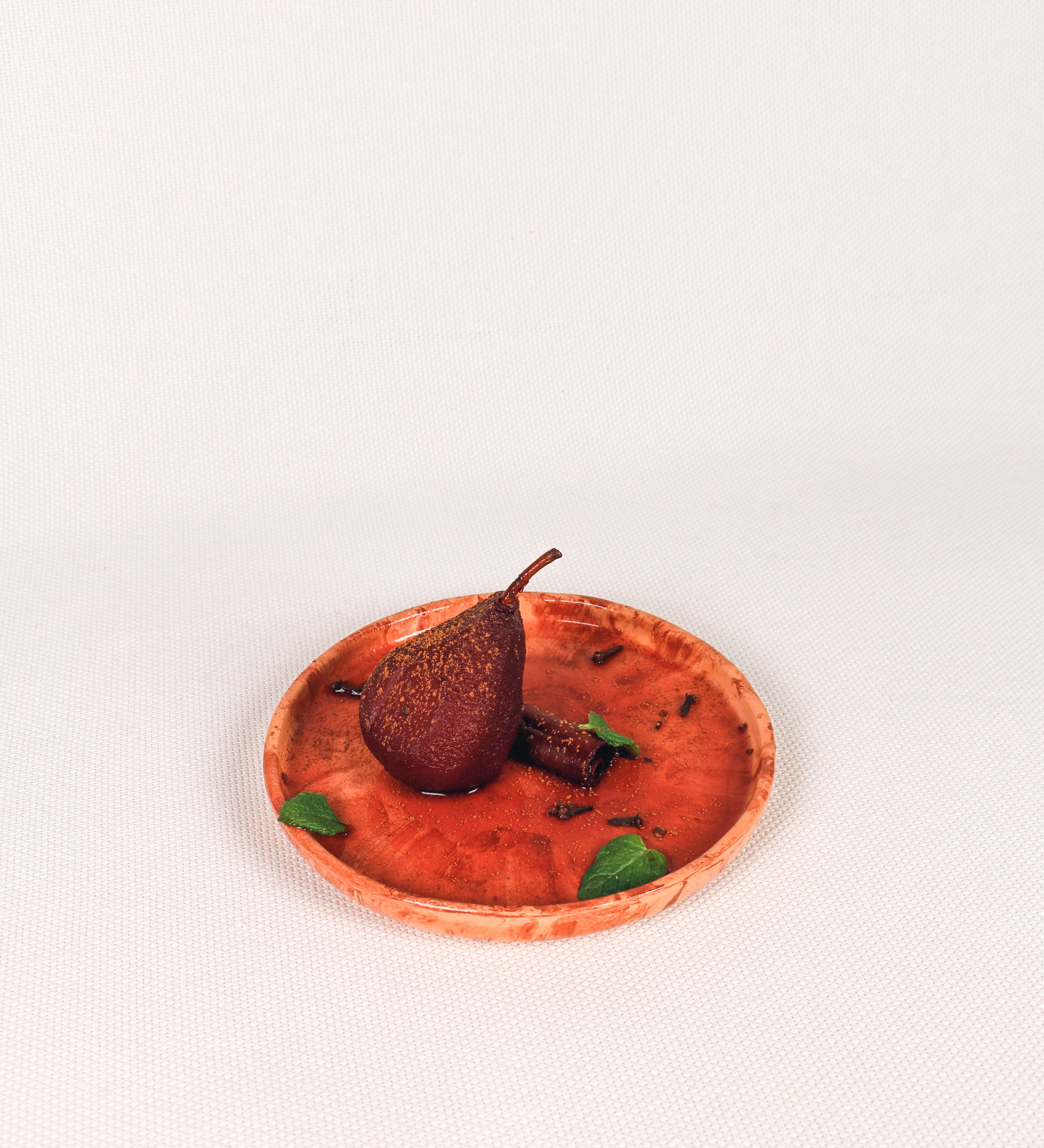 Prato de sobremesa com design minimalista e distinto. O prato é de barro, com uma mistura dois tipos de barro diferentes, um mais escuro e outro mais claro. Esta mistura cria um desenho de formas abstratas e aleatórias, que se espalham por todas as superfícies do prato. Tem um acabamento vidrado transparente com brilho, conferindo um toque de sofisticação e preservando os tons naturais dos barros. A forma do prato é circular, com uma borda envolvente de altura baixa e design simples e minimalista.