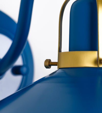 Aplique de parede com um design clássico e cores contemporâneas. O aplique é composto por uma base circular azul vintage, de onde se estende um braço curvo, que forma um arco gracioso e sustenta o chapéu do candeeiro, azul vintage também. O chapéu tem um formato cónico invertido, com uma borda ligeiramente levantada, que direciona a luz para baixo. O interior do chapéu é branco. No topo do chapéu, há um suporte circular em latão escovado, com três braços que fixa o chapéu ao braço curvo.