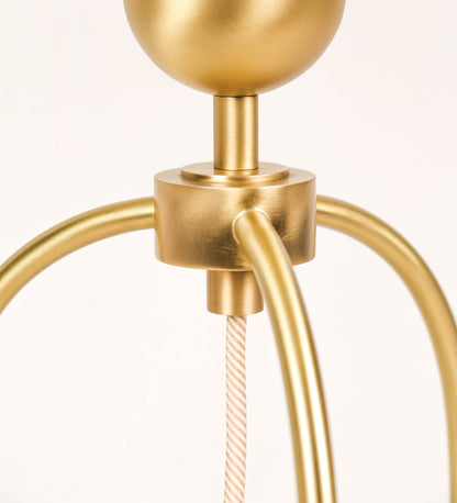 Candeeiro de mesa, em latão escovado, conferindo-lhe um tom dourado mate, com um design moderno e minimalista. O candeeiro tem o corpo com três pés curvados, terminando em pequenas esferas. A estrutura dos pés é interligada por uma peça central esférica. O cabo é revestido têxtil com um padrão de linhas douradas e brancas entrelaçadas, com interruptor e ficha transparentes. 