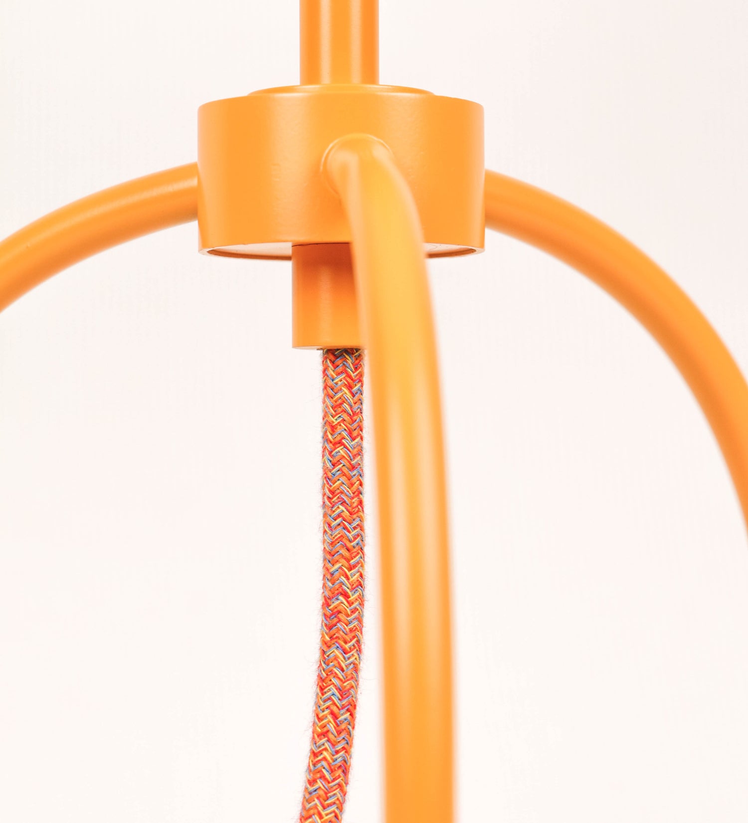 Candeeiro de mesa, de tom laranja-tangerina, com um design moderno e minimalista. O candeeiro tem o corpo com três pés curvados, terminando em pequenas esferas. A estrutura dos pés é interligada por uma peça central esférica. O cabo é revestido têxtil com um padrão de linhas coloridas, com interruptor e ficha transparentes. O abatjour é de forma cónica, em algodão, de tom bege claro com pequenas pintas escuras, semelhante à baunilha.