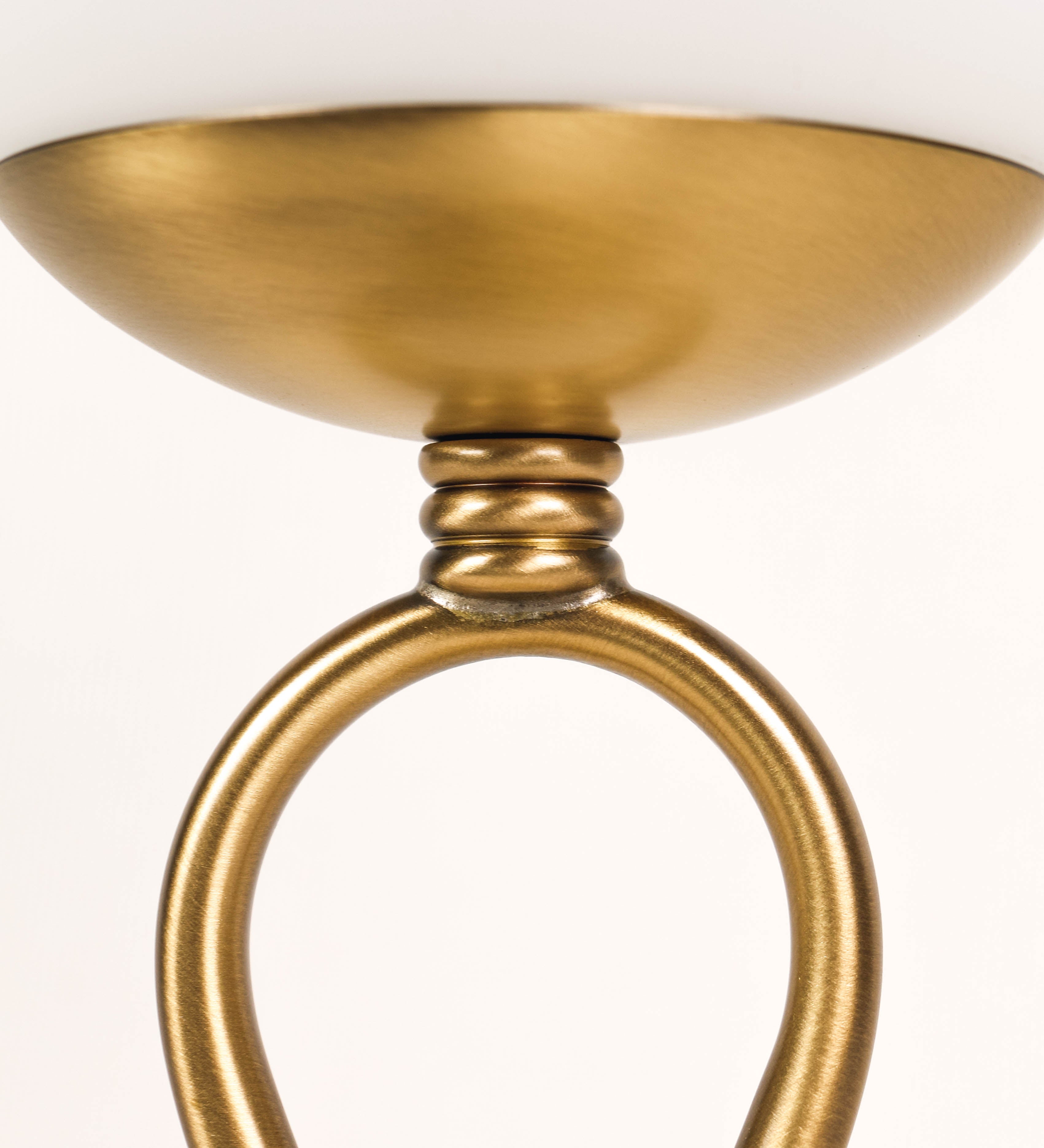 Candeeiro de mesa com um design clássico e sofisticado. O candeeiro possui uma base circular e robusta em latão com acabamento em ouro velho. A estrutura da base é complementada por um suporte em forma de nó, também em ouro velho, que se eleva graciosamente até ao suporte da luz. A luz é difundida através de uma esfera de vidro fosco branco, assente no corpo. O cabo é revestido têxtil com um padrão trançado de linhas douradas e brancas, com interruptor e ficha transparentes.