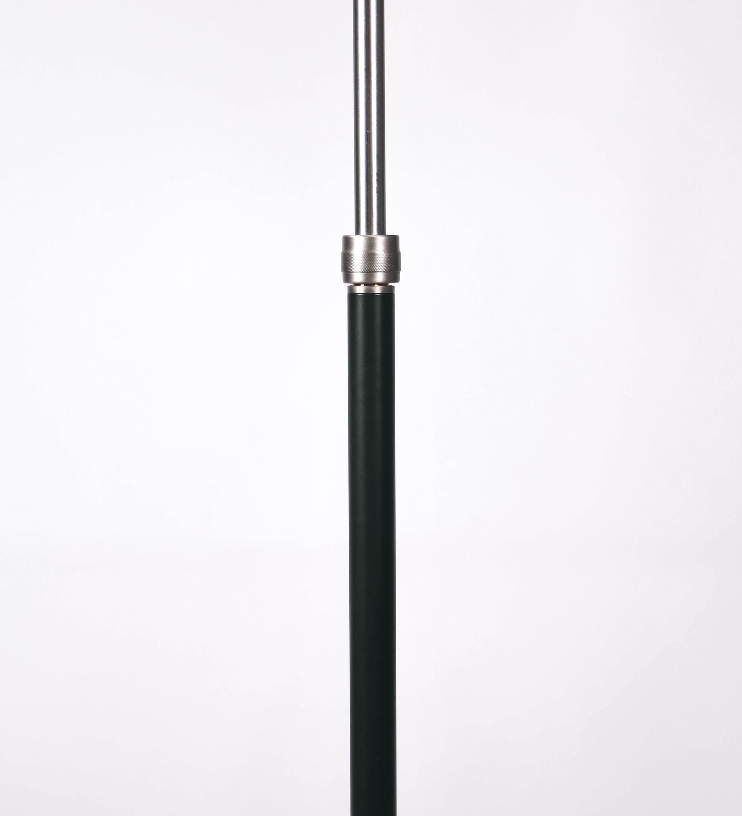 Candeeiro de pé com base circular em verde-azeitona. O corpo é fino e vertical, composto por uma haste verde-azeitona, e uma outra haste em níquel escovado, que permite ajustar a altura do candeeiro. A haste ajustável conecta a um braço horizontal, que sustenta o chapéu, e é manipulável. O chapéu é longo e arredondado, em verde-azeitona, e com uma pequena haste com uma esfera na ponta. O interior do chapéu é branco. O cabo é revestido têxtil em preto, com um interruptor de pé preto circular.