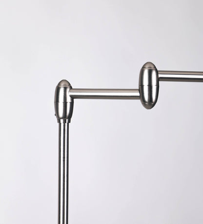 Candeeiro de pé com base circular em verde-azeitona. O corpo é fino e vertical, composto por uma haste verde-azeitona, e uma outra haste em níquel escovado, que permite ajustar a altura do candeeiro. A haste ajustável conecta a um braço horizontal, que sustenta o chapéu, e é manipulável. O chapéu é longo e arredondado, em verde-azeitona, e com uma pequena haste com uma esfera na ponta. O interior do chapéu é branco. O cabo é revestido têxtil em preto, com um interruptor de pé preto circular.