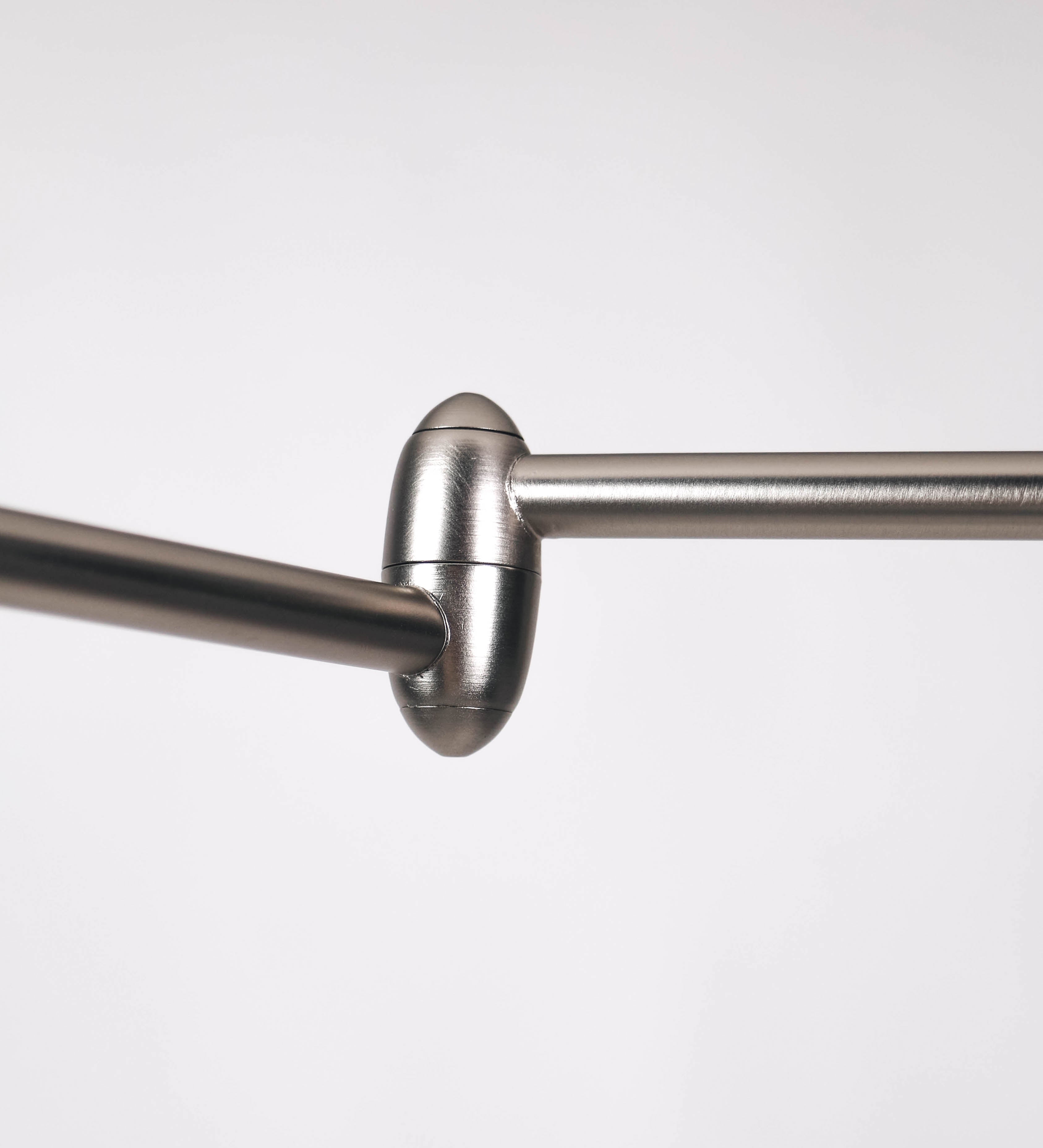 Candeeiro de pé com base circular em verde-azeitona. O corpo é fino e vertical, composto por uma haste verde-azeitona, e uma outra haste em níquel escovado, que permite ajustar a altura do candeeiro. A haste ajustável conecta a um braço horizontal, que sustenta o chapéu, e é manipulável. O chapéu é longo e arredondado, em verde-azeitona, e com uma pequena haste com uma esfera na ponta. O interior do chapéu é branco. O cabo é revestido têxtil em preto, com um interruptor de pé preto circular.