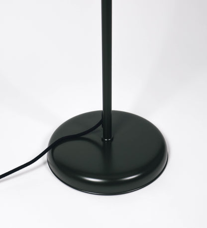 Candeeiro de pé com base circular em verde-azeitona. O corpo é fino e vertical, composto por uma haste verde-azeitona, e uma outra haste em níquel escovado, que permite ajustar a altura do candeeiro. A haste ajustável conecta a um braço horizontal, que sustenta o chapéu, e é manipulável. O chapéu é longo e arredondado, em verde-azeitona, e com uma pequena haste com uma esfera na ponta. O interior do chapéu é branco. O cabo é revestido têxtil em preto, com um interruptor de pé preto circular.