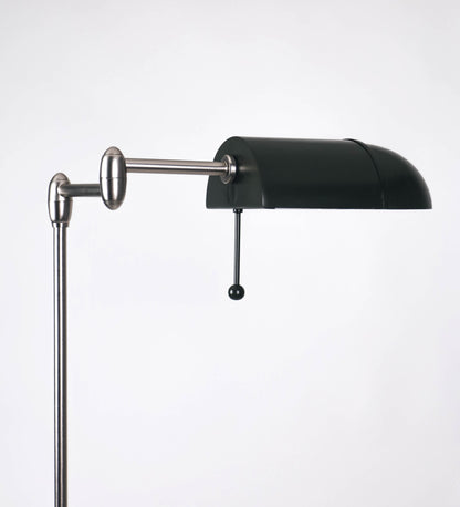 Candeeiro de pé com base circular em verde-azeitona. O corpo é fino e vertical, composto por uma haste verde-azeitona, e uma outra haste em níquel escovado, que permite ajustar a altura do candeeiro. A haste ajustável conecta a um braço horizontal, que sustenta o chapéu, e é manipulável. O chapéu é longo e arredondado, em verde-azeitona, e com uma pequena haste com uma esfera na ponta. O interior do chapéu é branco. O cabo é revestido têxtil em preto, com um interruptor de pé preto circular.
