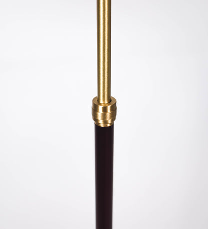Candeeiro de pé com base circular em tom vinho. O corpo é fino e vertical, composto por uma haste tom vinho, e uma outra haste em latão escovado, que permite ajustar a altura do candeeiro. A haste ajustável conecta a um braço horizontal, que sustenta o chapéu, e é manipulável. O chapéu é longo e arredondado, em tom vinho, e com uma pequena haste com uma esfera na ponta. O interior do chapéu é branco. O cabo é revestido têxtil em preto, com um interruptor de pé preto circular.