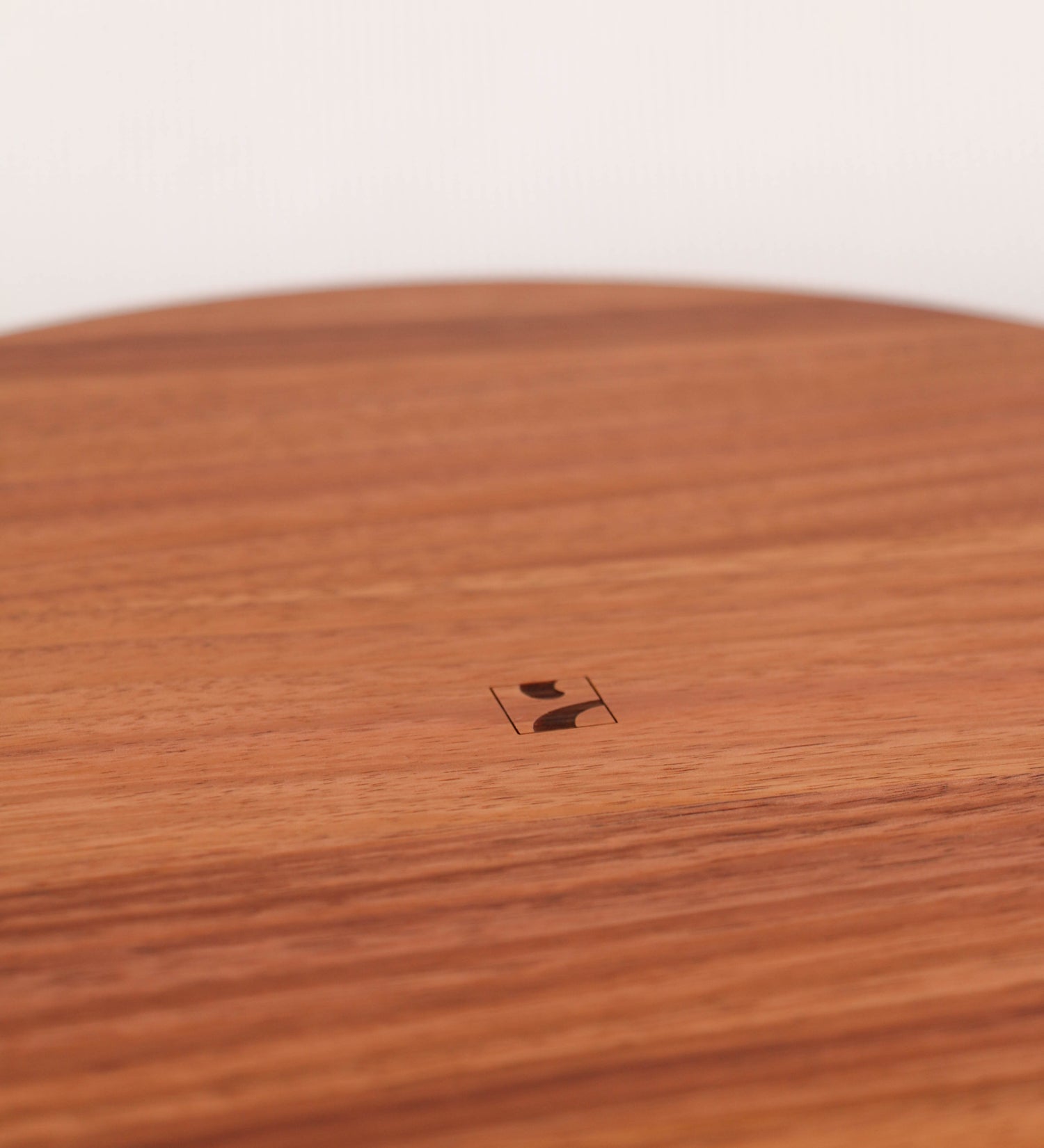 Fruteira com um design minimalista e distinto. A fruteira é de madeira de Acácia-Austrália, com uma tonalidade escura e verniz foodsafe semi-brilhante. A peça é de formato circular e com uma borda de cerca de 3 cm de altura, decorada com relevos lineares dispostos horizontalmente, tipo ranhuras, que envolvem a fruteira.
