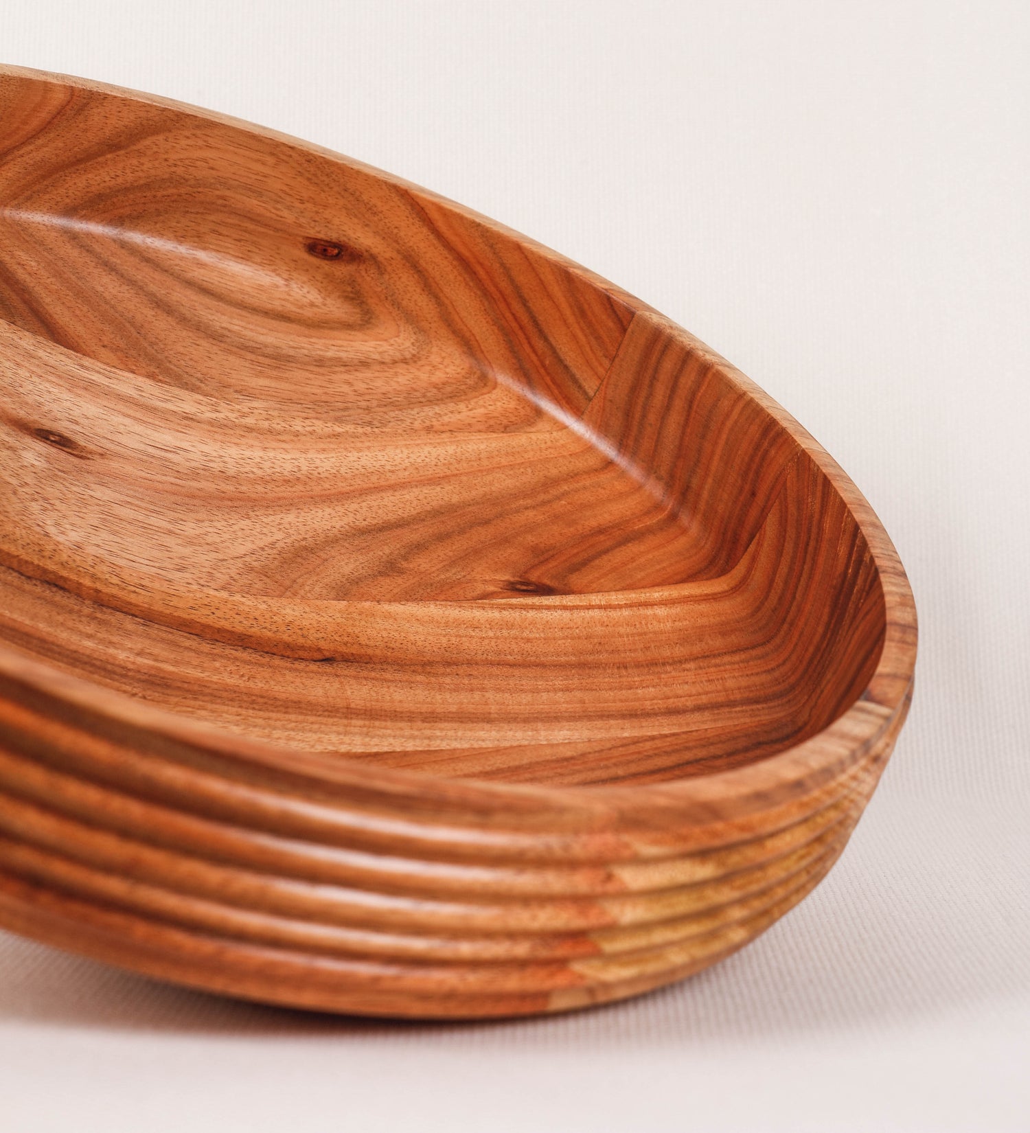 Fruteira com um design minimalista e distinto. A fruteira é de madeira de Acácia-Austrália, com uma tonalidade escura e verniz foodsafe semi-brilhante. A peça é de formato cónico e com um toque liso, semelhante a um pião, com uma ponteira em madeira também de tom mais escuro, quase negro. Apresenta ainda uma borda de cerca de 3 cm de altura, próxima da abertura da peça, decorada com relevos lineares dispostos horizontalmente, tipo ranhuras, que envolvem a fruteira.
