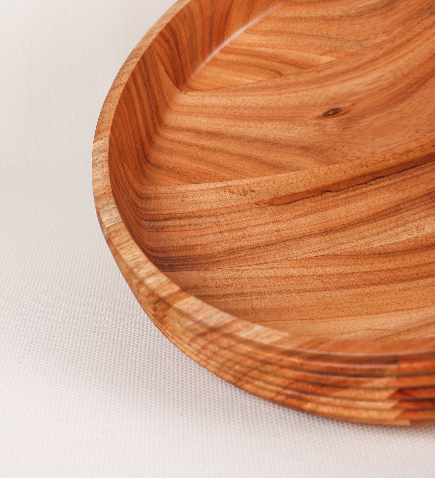 Fruteira com um design minimalista e distinto. A fruteira é de madeira de Acácia-Austrália, com uma tonalidade escura e verniz foodsafe semi-brilhante. A peça é de formato cónico e com um toque liso, semelhante a um pião, com uma ponteira em madeira também de tom mais escuro, quase negro. Apresenta ainda uma borda de cerca de 3 cm de altura, próxima da abertura da peça, decorada com relevos lineares dispostos horizontalmente, tipo ranhuras, que envolvem a fruteira.