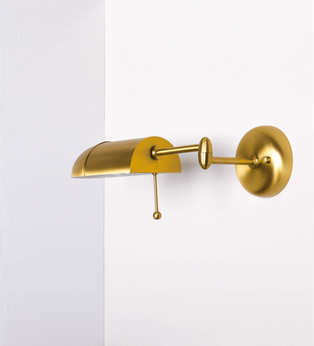 Aplique de parede com um design elegante e funcional. A base do aplique é redonda e fixa-se diretamente na parede. Do centro da sua base sai o braço do aplique, que é reto e horizontal. O braço é ajustável permitindo direcionar a luz. No final do braço, há um chapéu longo e arredondado e com uma pequena haste com uma esfera na ponta, que auxilia a movimentar o chapéu. 