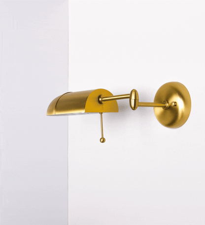 Aplique de parede com um design elegante e funcional. A base do aplique é redonda e fixa-se diretamente na parede. Do centro da sua base sai o braço do aplique, que é reto e horizontal. O braço é ajustável permitindo direcionar a luz. No final do braço, há um chapéu longo e arredondado e com uma pequena haste com uma esfera na ponta, que auxilia a movimentar o chapéu. 