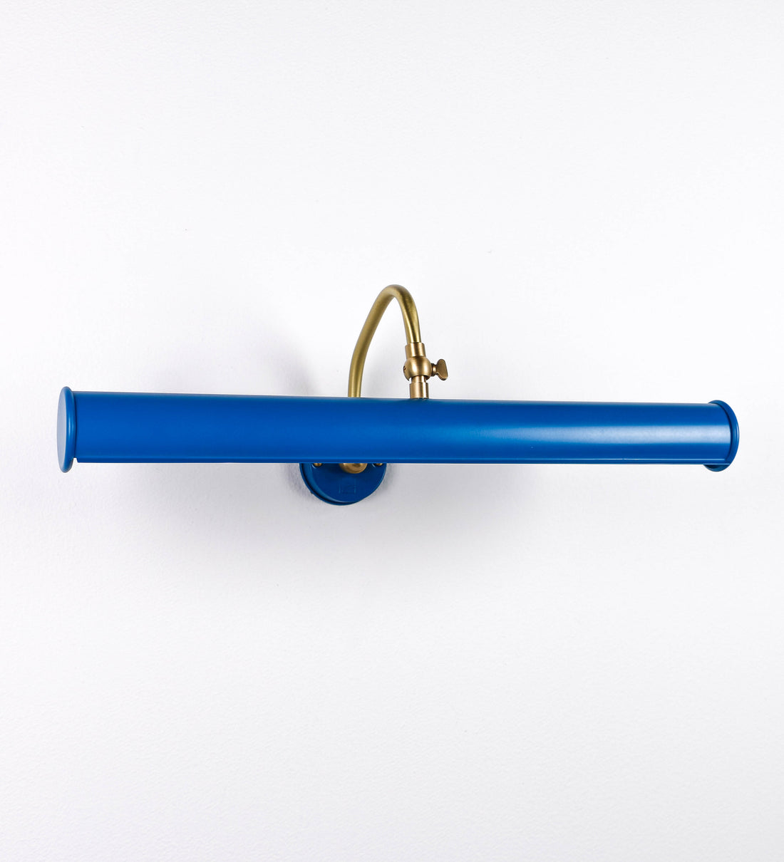 Aplique de parede que combina elementos clássicos com toques contemporâneos. O aplique é composto por uma base circular azul vintage de onde se estende um braço curvo e gracioso, em latão escovado, que suporta a barra principal. O braço contém um elemento, em latão escovado, que permite apertar ou desapertar a barra para melhor manipular a direção da luz. A barra de 45cm de largura, é cilíndrica e alongada, azul vintage. As extremidades do cilindro são planas e do mesmo diâmetro.