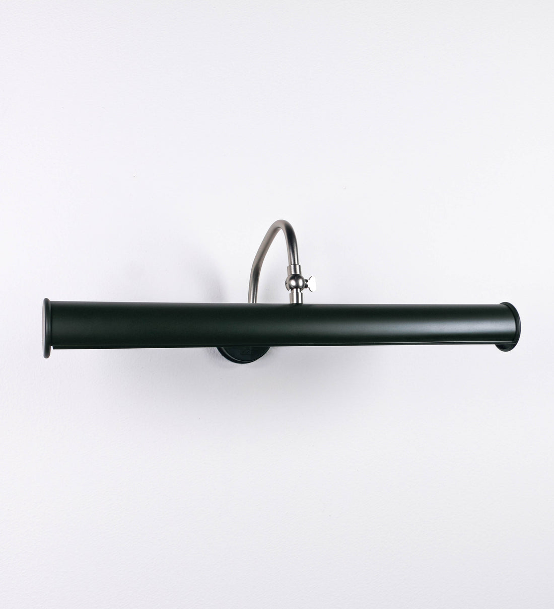 Aplique de parede que combina elementos clássicos com toques contemporâneos. O aplique é composto por uma base circular verde-azeitona, de onde se estende um braço curvo e gracioso, em níquel escovado, que suporta a barra principal. O braço contém um elemento, em níquel escovado, que permite apertar ou desapertar a barra para melhor manipular a direção da luz. A barra de 45cm de largura, é cilíndrica e alongada, verde-azeitona. As extremidades do cilindro são planas e do mesmo diâmetro.