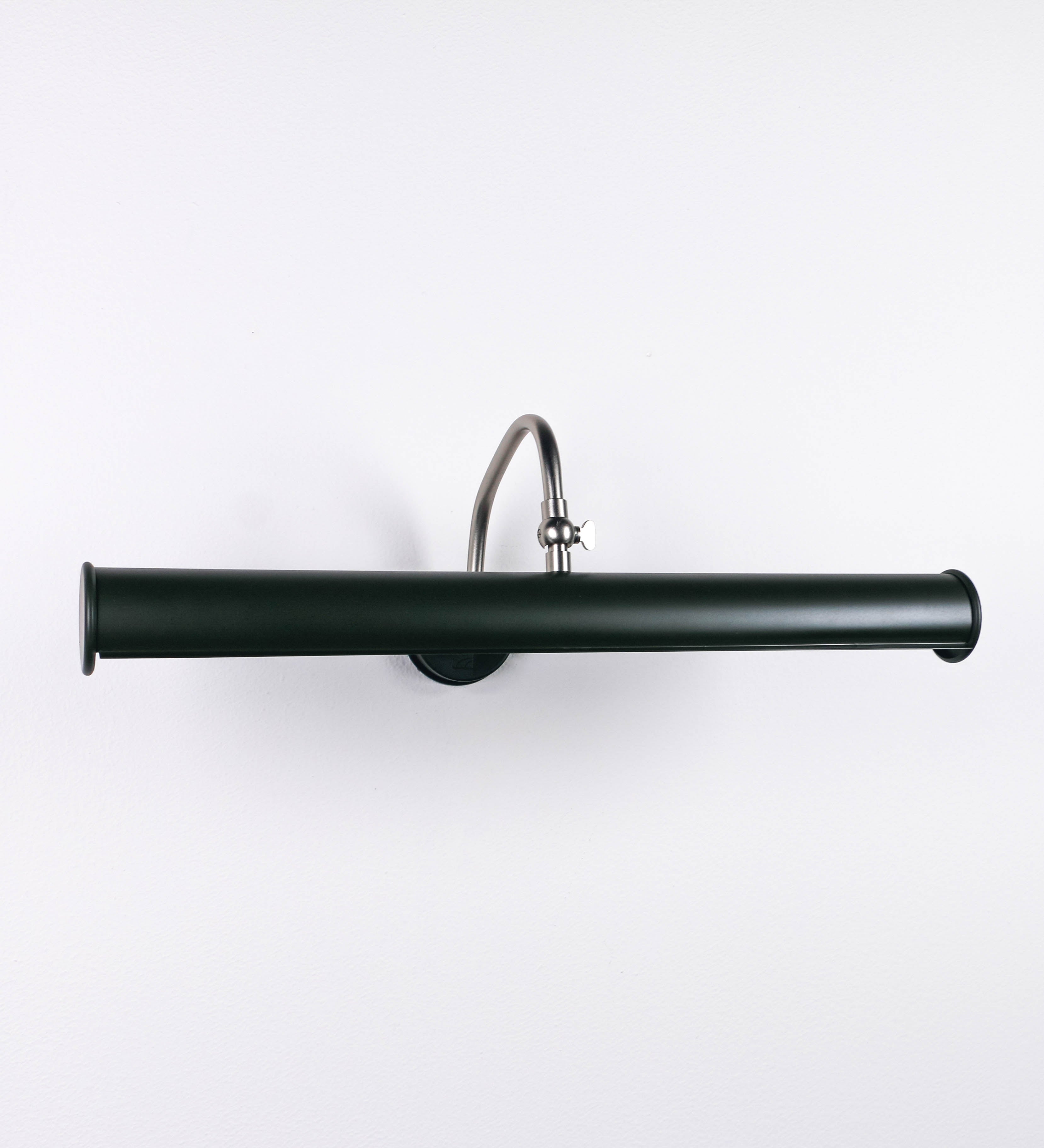 Aplique de parede que combina elementos clássicos com toques contemporâneos. O aplique é composto por uma base circular verde-azeitona, de onde se estende um braço curvo e gracioso, em níquel escovado, que suporta a barra principal. O braço contém um elemento, em níquel escovado, que permite apertar ou desapertar a barra para melhor manipular a direção da luz. A barra de 45cm de largura, é cilíndrica e alongada, verde-azeitona. As extremidades do cilindro são planas e do mesmo diâmetro.