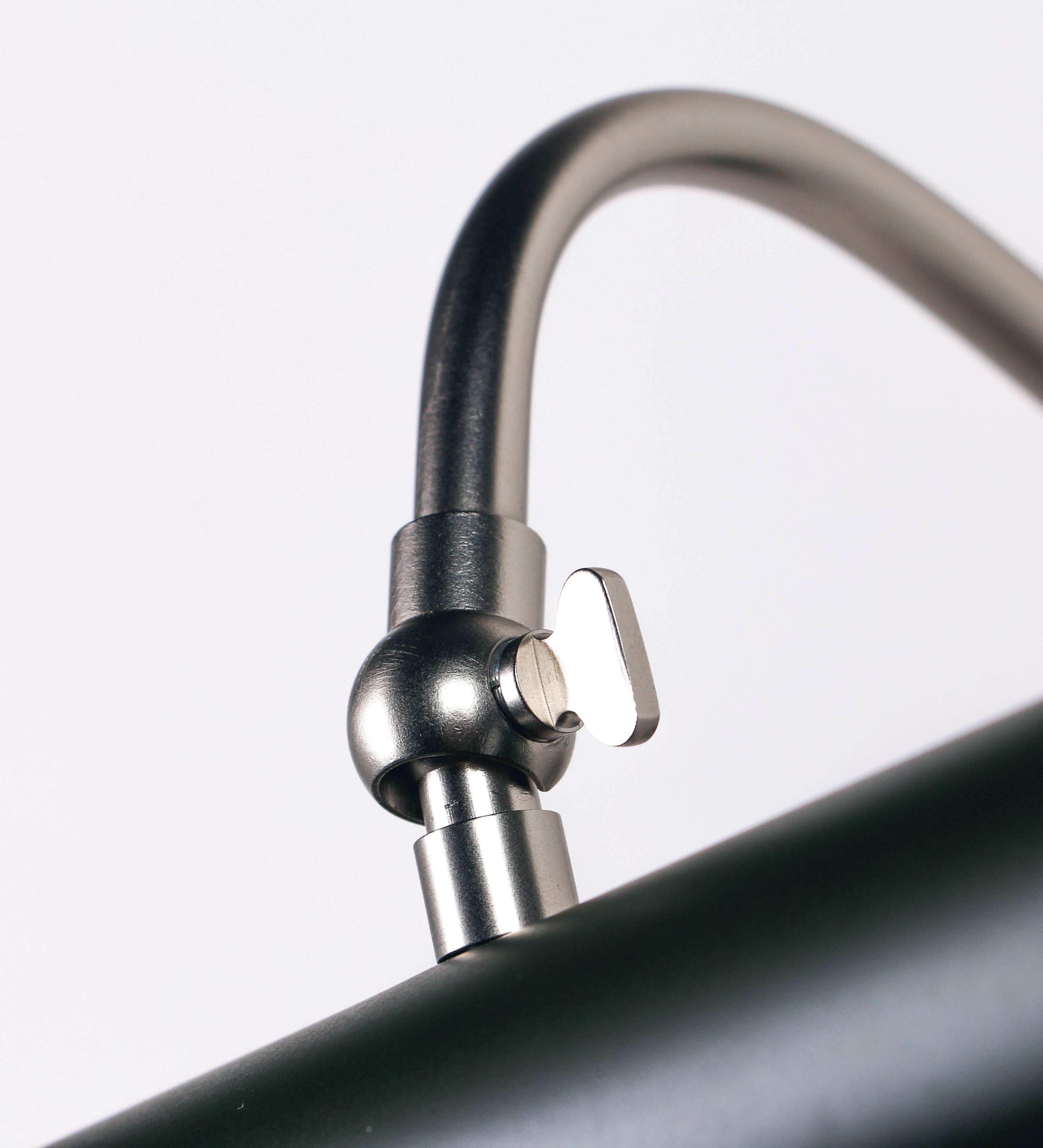 Aplique de parede que combina elementos clássicos com toques contemporâneos. O aplique é composto por uma base circular verde-azeitona, de onde se estende um braço curvo e gracioso, em níquel escovado, que suporta a barra principal. O braço contém um elemento, em níquel escovado, que permite apertar ou desapertar a barra para melhor manipular a direção da luz. A barra de 45cm de largura, é cilíndrica e alongada, verde-azeitona. As extremidades do cilindro são planas e do mesmo diâmetro.