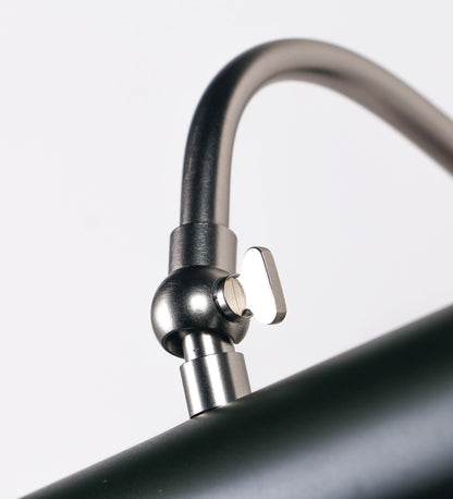 Aplique de parede que combina elementos clássicos com toques contemporâneos. O aplique é composto por uma base circular verde-azeitona, de onde se estende um braço curvo e gracioso, em níquel escovado, que suporta a barra principal. O braço contém um elemento, em níquel escovado, que permite apertar ou desapertar a barra para melhor manipular a direção da luz. A barra de 45cm de largura, é cilíndrica e alongada, verde-azeitona. As extremidades do cilindro são planas e do mesmo diâmetro.