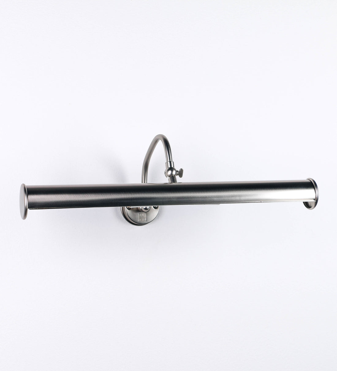 Aplique de parede que combina elementos clássicos com toques contemporâneos, todo em níquel escovado. O aplique é composto por uma base circular de onde se estende um braço curvo e gracioso, que suporta a barra principal. O braço contém um elemento que permite apertar ou desapertar a barra para melhor manipular a direção da luz. A barra de 45cm de largura é cilíndrica e alongada. As extremidades do cilindro são planas e do mesmo diâmetro.