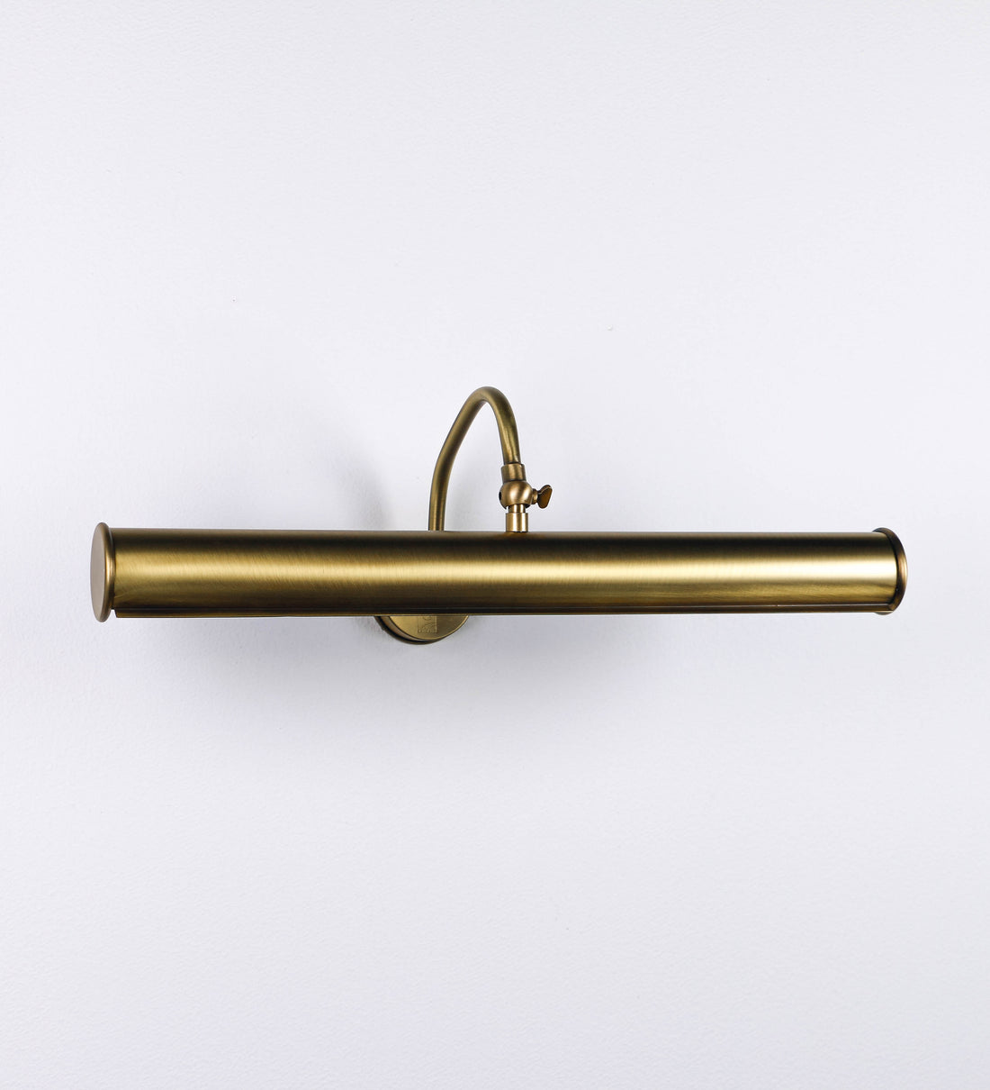 Aplique de parede que combina elementos clássicos com toques contemporâneos, todo em ouro velho. O aplique é composto por uma base circular de onde se estende um braço curvo e gracioso, que suporta a barra principal. O braço contém um elemento que permite apertar ou desapertar a barra para melhor manipular a direção da luz. A barra de 45cm de largura é cilíndrica e alongada. As extremidades do cilindro são planas e do mesmo diâmetro.