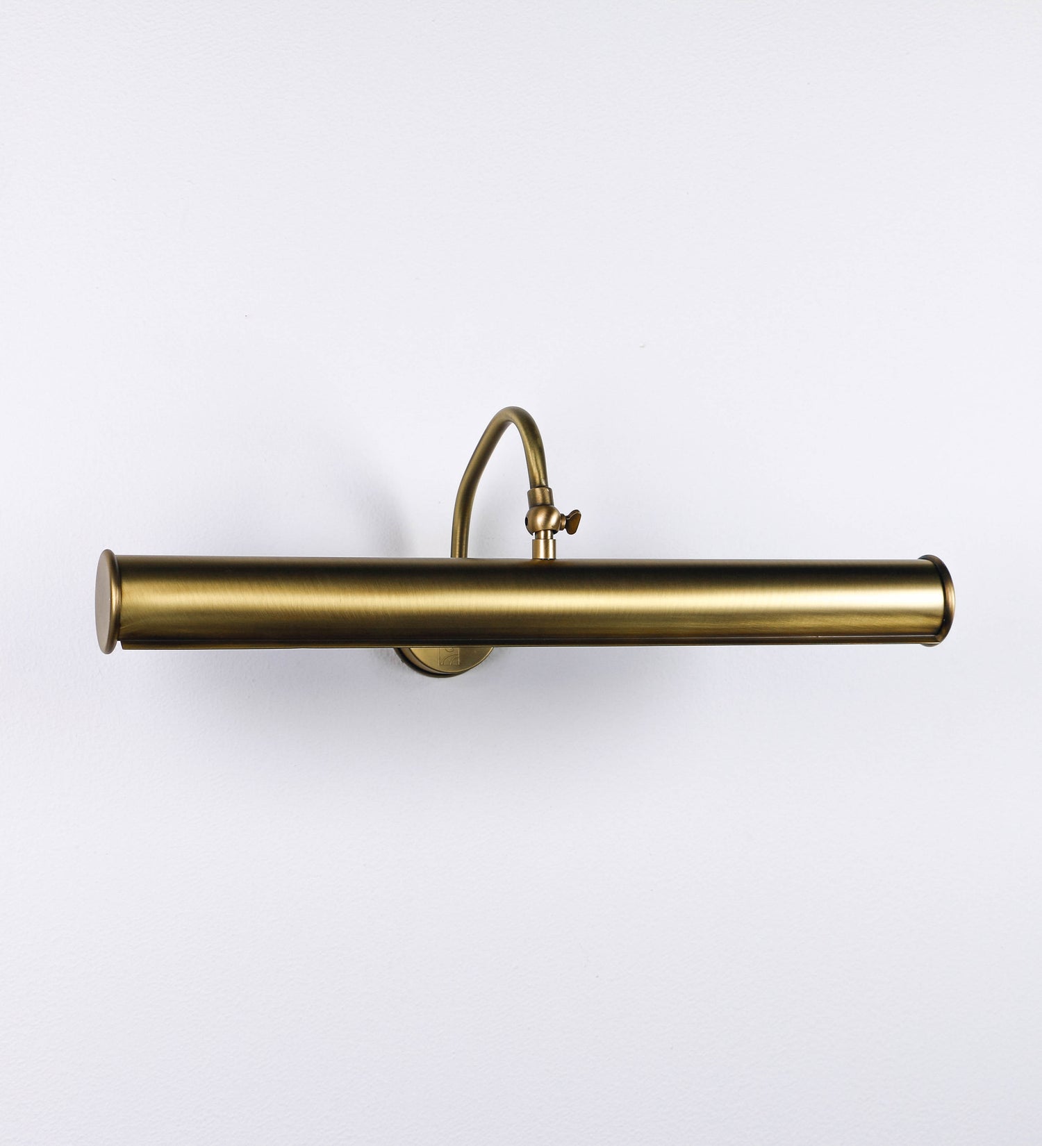 Aplique de parede que combina elementos clássicos com toques contemporâneos, todo em ouro velho. O aplique é composto por uma base circular de onde se estende um braço curvo e gracioso, que suporta a barra principal. O braço contém um elemento que permite apertar ou desapertar a barra para melhor manipular a direção da luz. A barra de 45cm de largura é cilíndrica e alongada. As extremidades do cilindro são planas e do mesmo diâmetro.