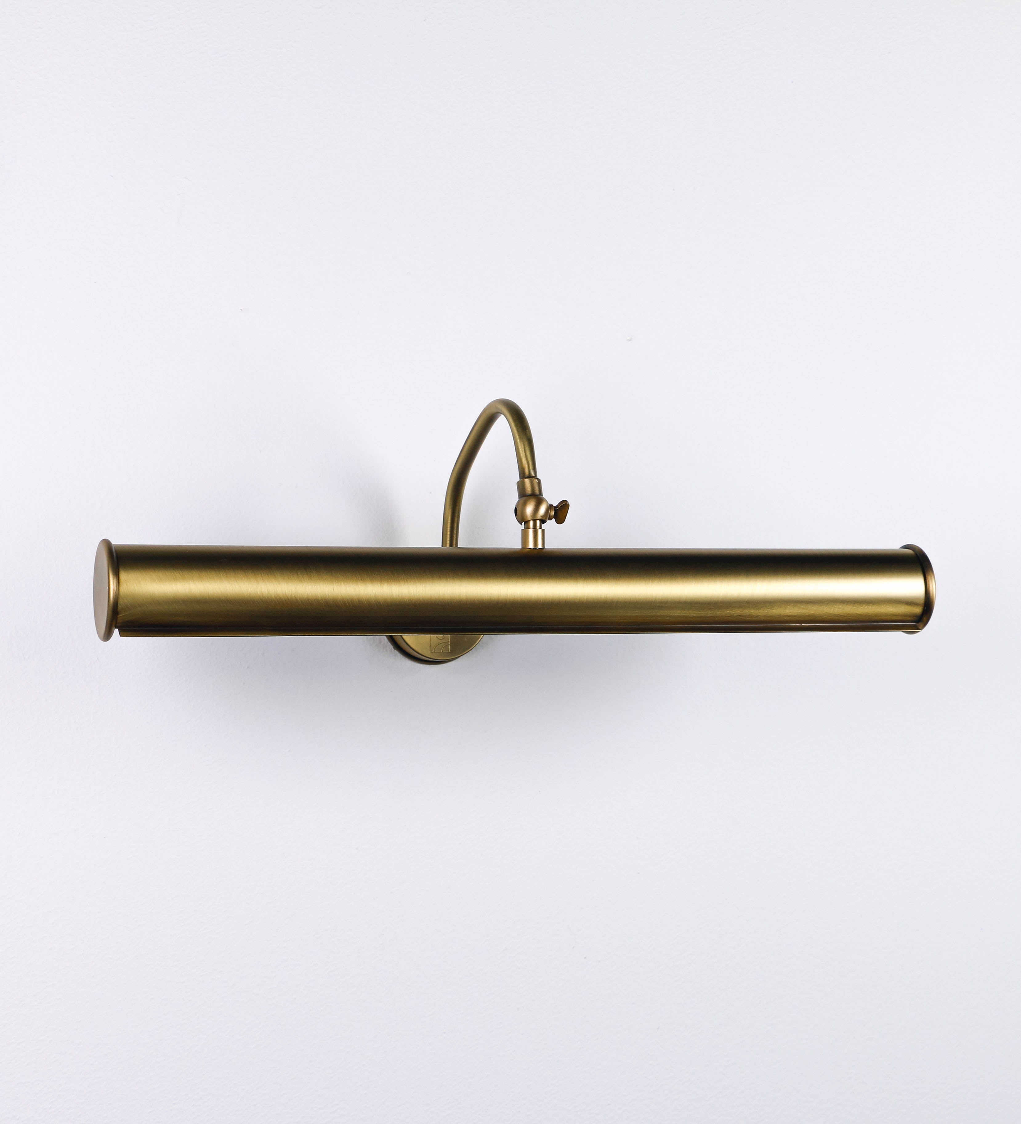 Aplique de parede que combina elementos clássicos com toques contemporâneos, todo em ouro velho. O aplique é composto por uma base circular de onde se estende um braço curvo e gracioso, que suporta a barra principal. O braço contém um elemento que permite apertar ou desapertar a barra para melhor manipular a direção da luz. A barra de 45cm de largura é cilíndrica e alongada. As extremidades do cilindro são planas e do mesmo diâmetro.