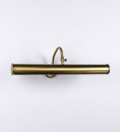 Aplique de parede que combina elementos clássicos com toques contemporâneos, todo em ouro velho. O aplique é composto por uma base circular de onde se estende um braço curvo e gracioso, que suporta a barra principal. O braço contém um elemento que permite apertar ou desapertar a barra para melhor manipular a direção da luz. A barra de 45cm de largura é cilíndrica e alongada. As extremidades do cilindro são planas e do mesmo diâmetro.