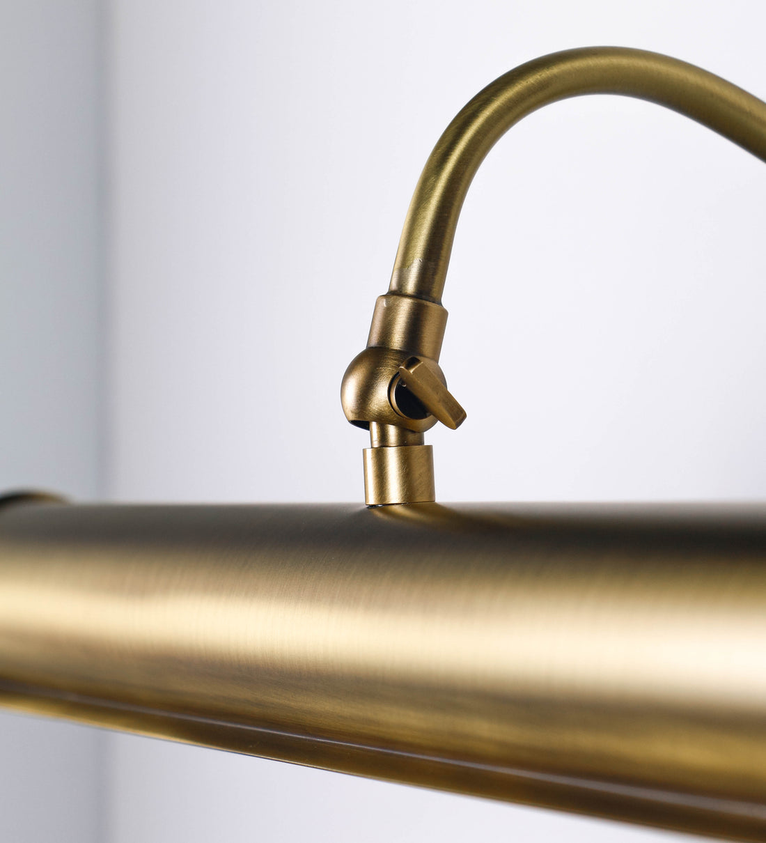 Aplique de parede que combina elementos clássicos com toques contemporâneos, todo em ouro velho. O aplique é composto por uma base circular de onde se estende um braço curvo e gracioso, que suporta a barra principal. O braço contém um elemento que permite apertar ou desapertar a barra para melhor manipular a direção da luz. A barra de 45cm de largura é cilíndrica e alongada. As extremidades do cilindro são planas e do mesmo diâmetro.
