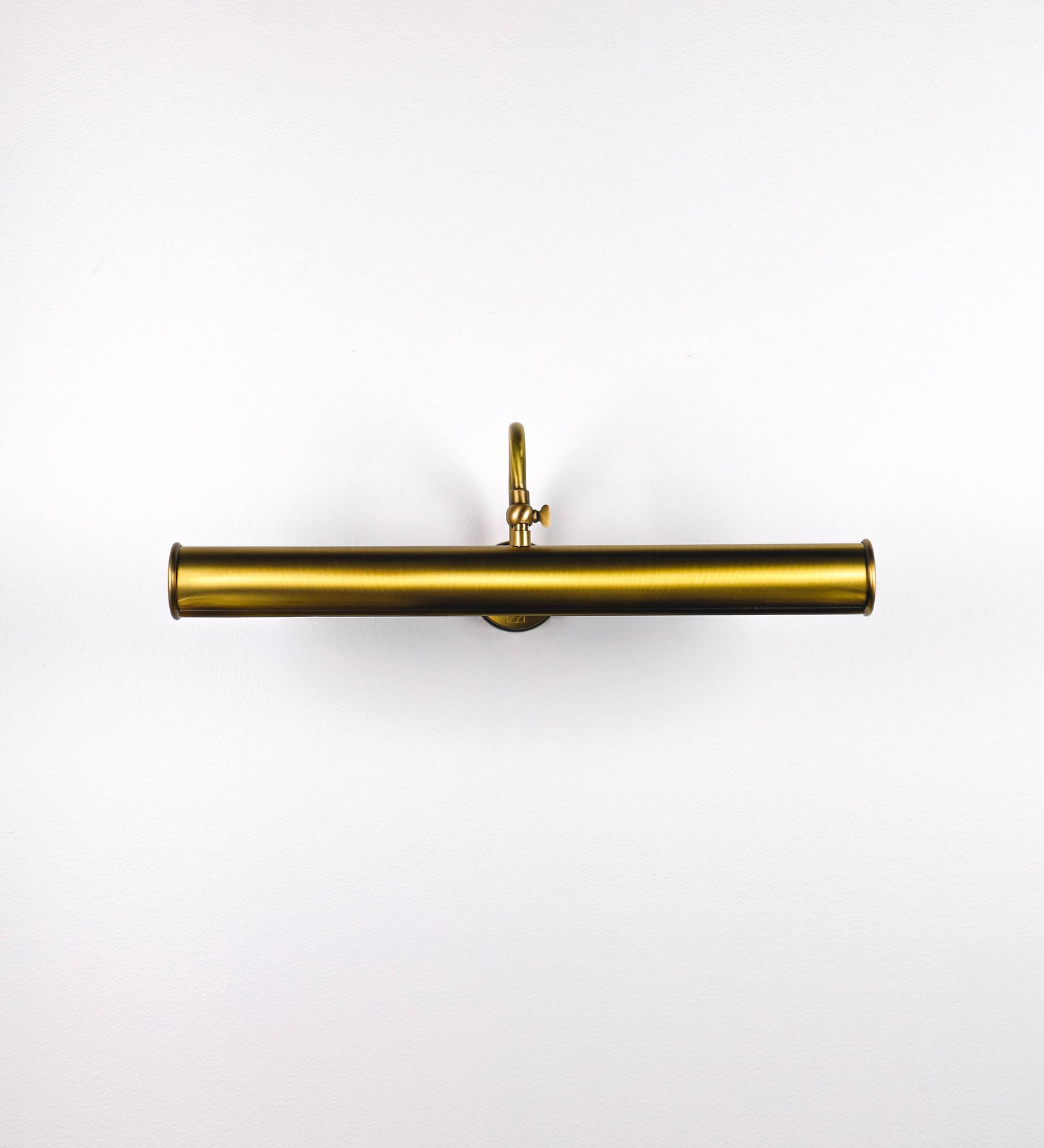 Aplique de parede que combina elementos clássicos com toques contemporâneos, todo em ouro velho. O aplique é composto por uma base circular de onde se estende um braço curvo e gracioso, que suporta a barra principal. O braço contém um elemento que permite apertar ou desapertar a barra para melhor manipular a direção da luz. A barra de 45cm de largura é cilíndrica e alongada. As extremidades do cilindro são planas e do mesmo diâmetro.