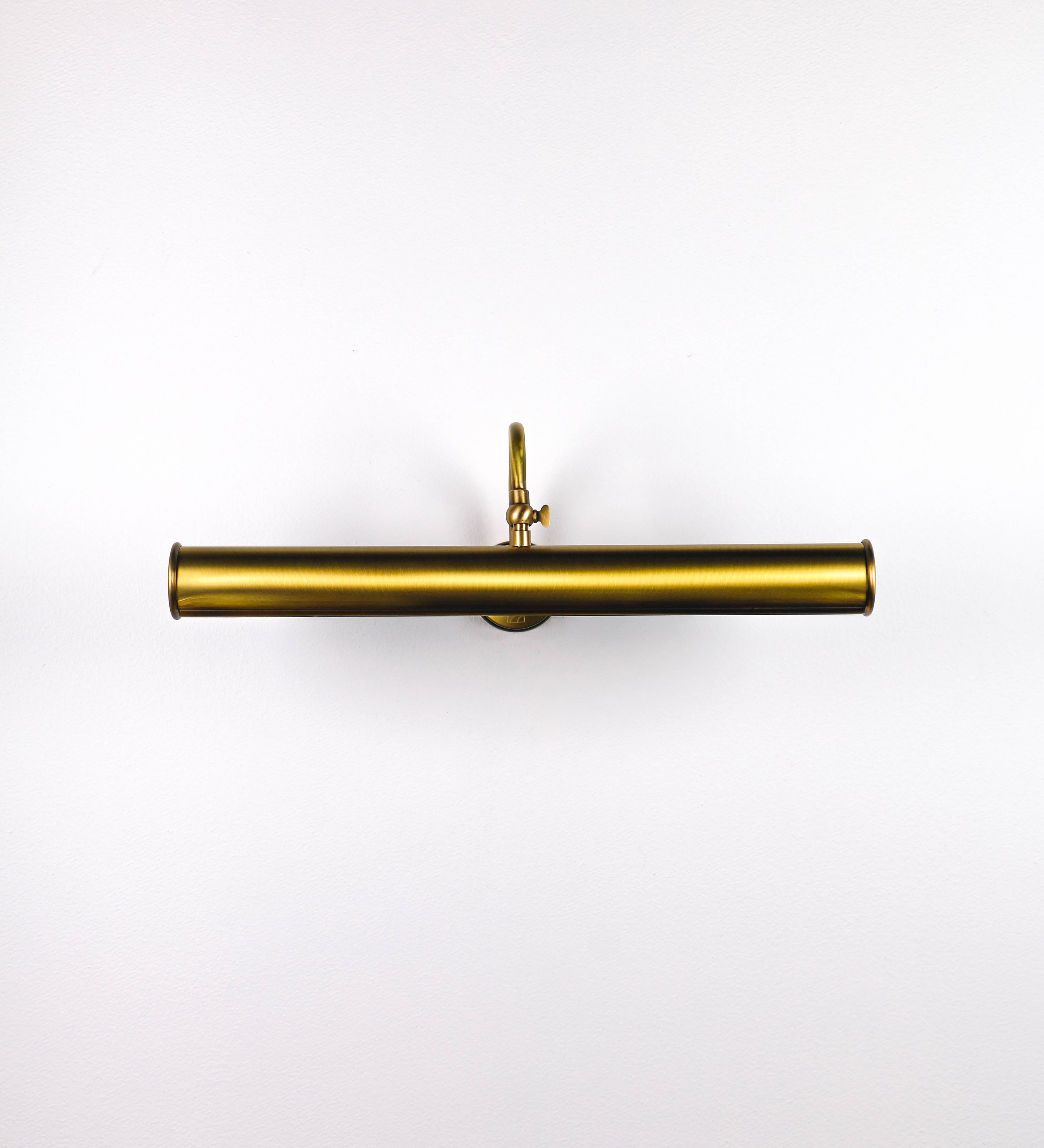 Aplique de parede que combina elementos clássicos com toques contemporâneos, todo em ouro velho. O aplique é composto por uma base circular de onde se estende um braço curvo e gracioso, que suporta a barra principal. O braço contém um elemento que permite apertar ou desapertar a barra para melhor manipular a direção da luz. A barra de 45cm de largura é cilíndrica e alongada. As extremidades do cilindro são planas e do mesmo diâmetro.