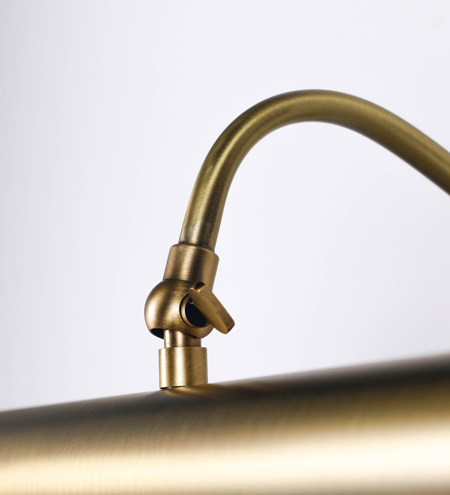 Aplique de parede que combina elementos clássicos com toques contemporâneos, todo em ouro velho. O aplique é composto por uma base circular de onde se estende um braço curvo e gracioso, que suporta a barra principal. O braço contém um elemento que permite apertar ou desapertar a barra para melhor manipular a direção da luz. A barra de 45cm de largura é cilíndrica e alongada. As extremidades do cilindro são planas e do mesmo diâmetro.