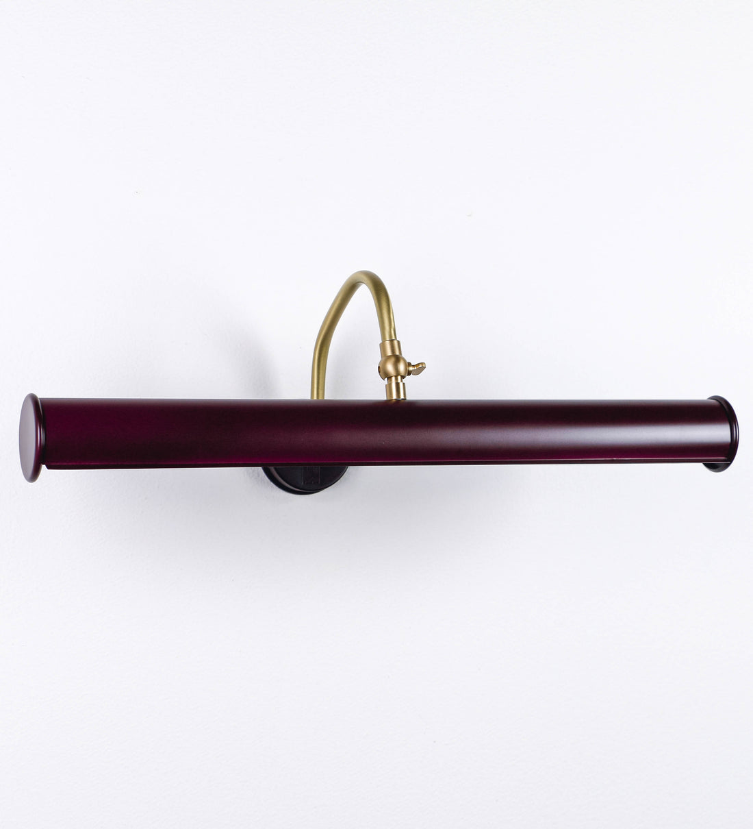 Aplique de parede que combina elementos clássicos com toques contemporâneos. O aplique é composto por uma base circular tom vinho, de onde se estende um braço curvo e gracioso, em latão escovado, que suporta a barra principal. O braço contém um elemento, em latão escovado, que permite apertar ou desapertar a barra para melhor manipular a direção da luz. A barra de 45cm de largura, é cilíndrica e alongada, tom vinho. As extremidades do cilindro são planas e do mesmo diâmetro.