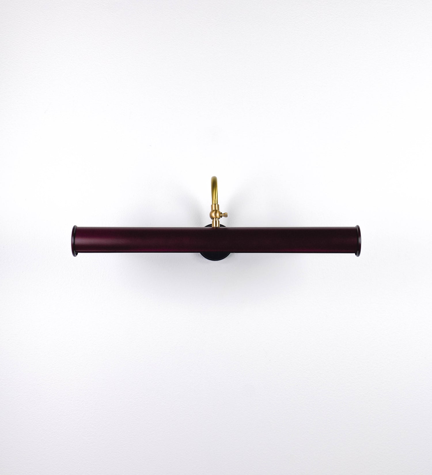 Aplique de parede que combina elementos clássicos com toques contemporâneos. O aplique é composto por uma base circular tom vinho, de onde se estende um braço curvo e gracioso, em latão escovado, que suporta a barra principal. O braço contém um elemento, em latão escovado, que permite apertar ou desapertar a barra para melhor manipular a direção da luz. A barra de 45cm de largura, é cilíndrica e alongada, tom vinho. As extremidades do cilindro são planas e do mesmo diâmetro.