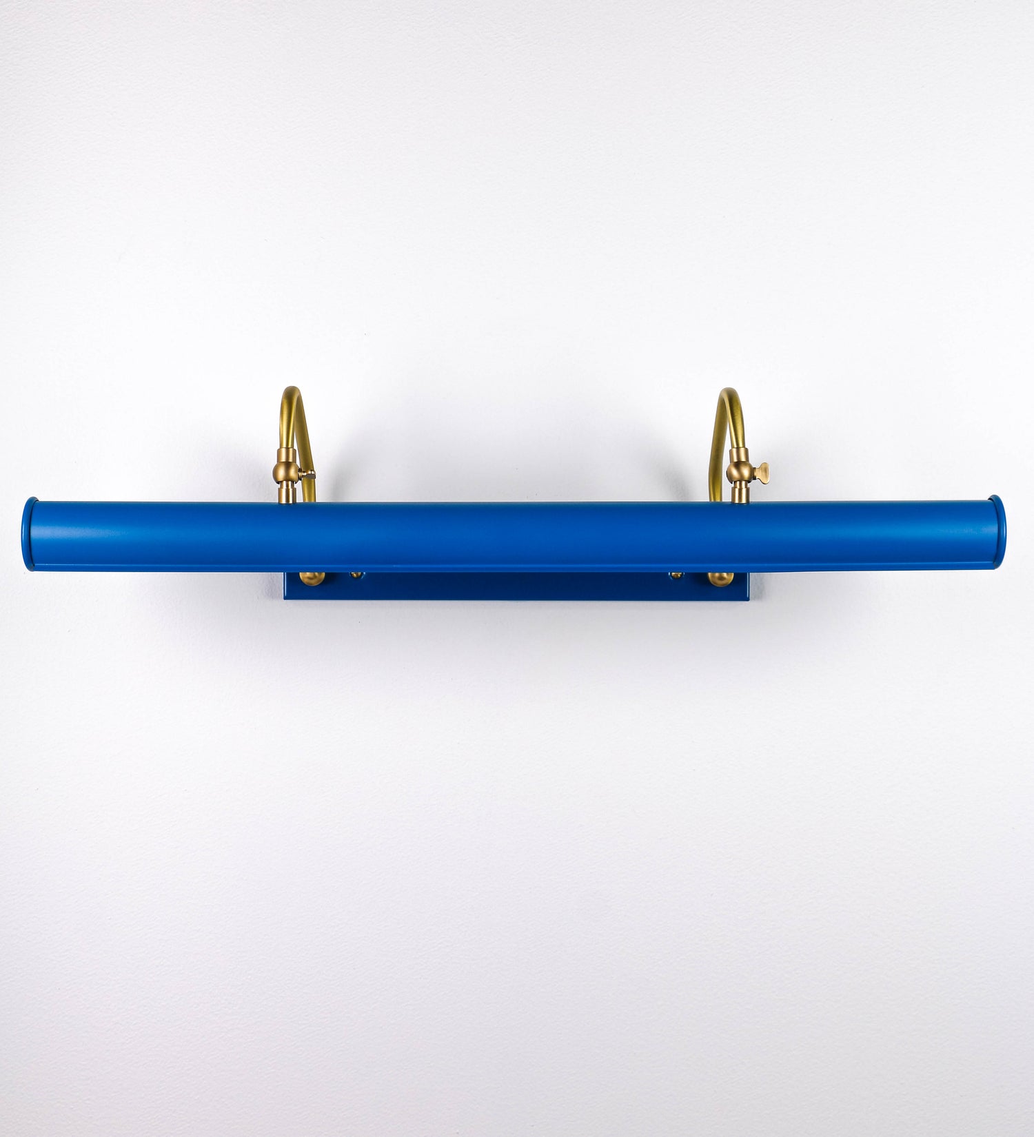 Aplique de parede que combina elementos clássicos com toques contemporâneos. O aplique é composto por uma base retangular azul vintage, de onde se estendem dois braços curvos e graciosos, em latão escovado, que suportam a barra principal. Os braços contêm um elemento, em latão escovado, que permite apertar ou desapertar a barra para melhor manipular a direção da luz. A barra de 65cm de largura, é cilíndrica e alongada, azul vintage. As extremidades do cilindro são planas e do mesmo diâmetro.