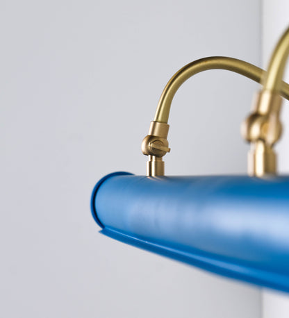 Aplique de parede que combina elementos clássicos com toques contemporâneos. O aplique é composto por uma base retangular azul vintage, de onde se estendem dois braços curvos e graciosos, em latão escovado, que suportam a barra principal. Os braços contêm um elemento, em latão escovado, que permite apertar ou desapertar a barra para melhor manipular a direção da luz. A barra de 65cm de largura, é cilíndrica e alongada, azul vintage. As extremidades do cilindro são planas e do mesmo diâmetro.