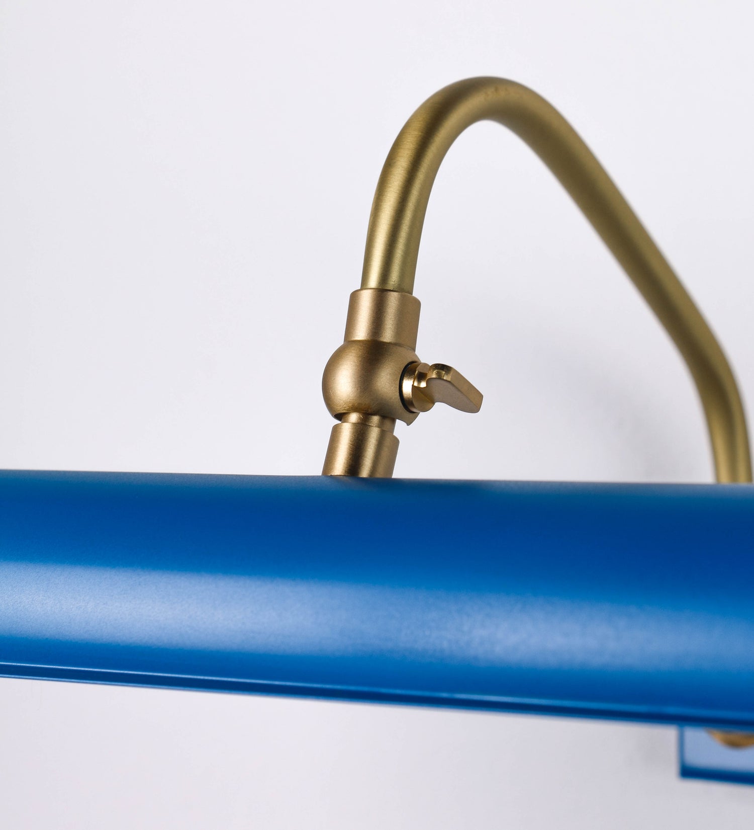 Aplique de parede que combina elementos clássicos com toques contemporâneos. O aplique é composto por uma base retangular azul vintage, de onde se estendem dois braços curvos e graciosos, em latão escovado, que suportam a barra principal. Os braços contêm um elemento, em latão escovado, que permite apertar ou desapertar a barra para melhor manipular a direção da luz. A barra de 65cm de largura, é cilíndrica e alongada, azul vintage. As extremidades do cilindro são planas e do mesmo diâmetro.