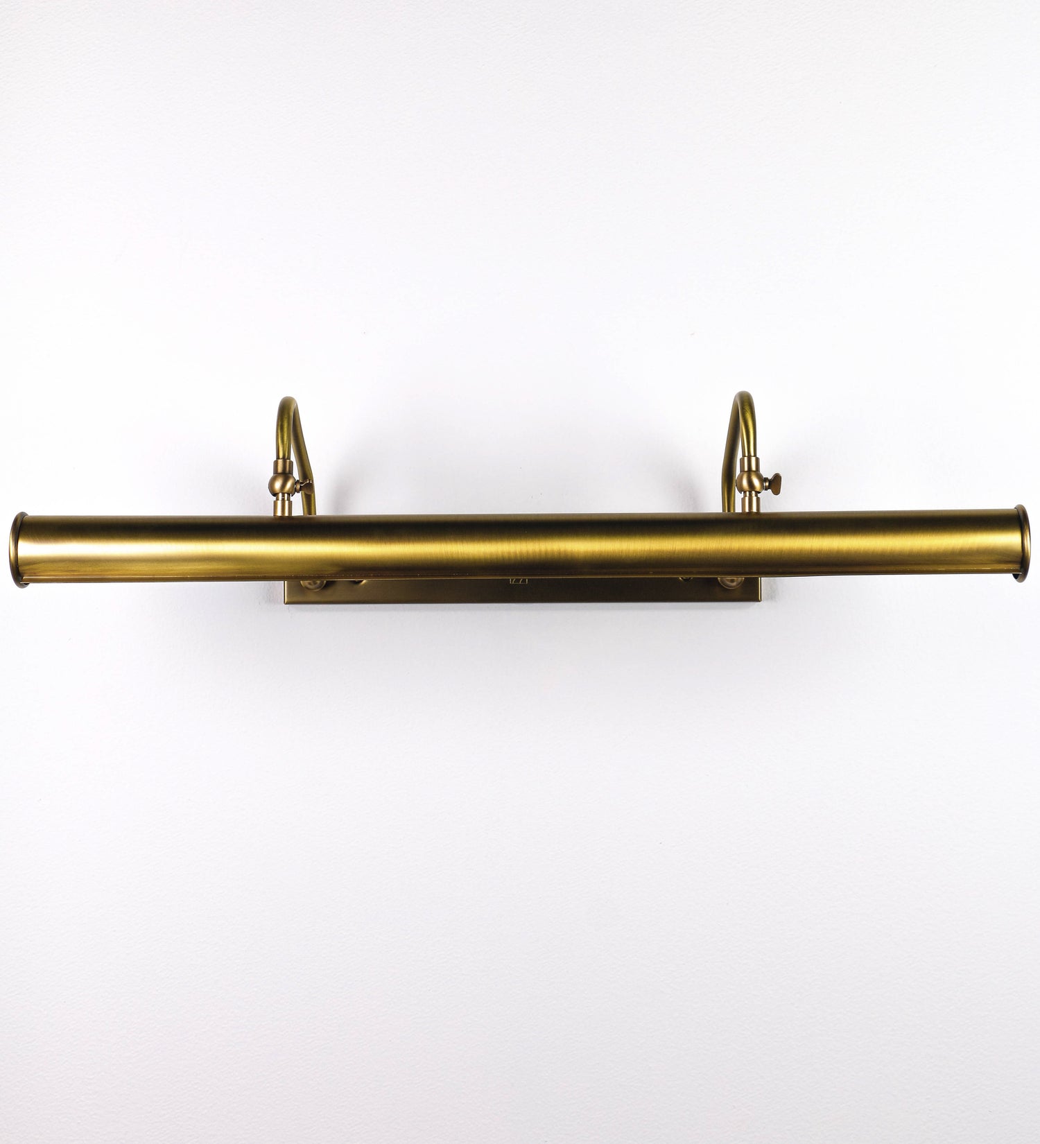 Aplique de parede que combina elementos clássicos com toques contemporâneos, todo em ouro velho. O aplique é composto por uma base retangular, de onde se estendem dois braços curvos e graciosos, que suportam a barra principal. Os braços contêm um elemento que permite apertar ou desapertar a barra para melhor manipular a direção da luz. A barra de 65cm de largura é cilíndrica e alongada. As extremidades do cilindro são planas e do mesmo diâmetro.