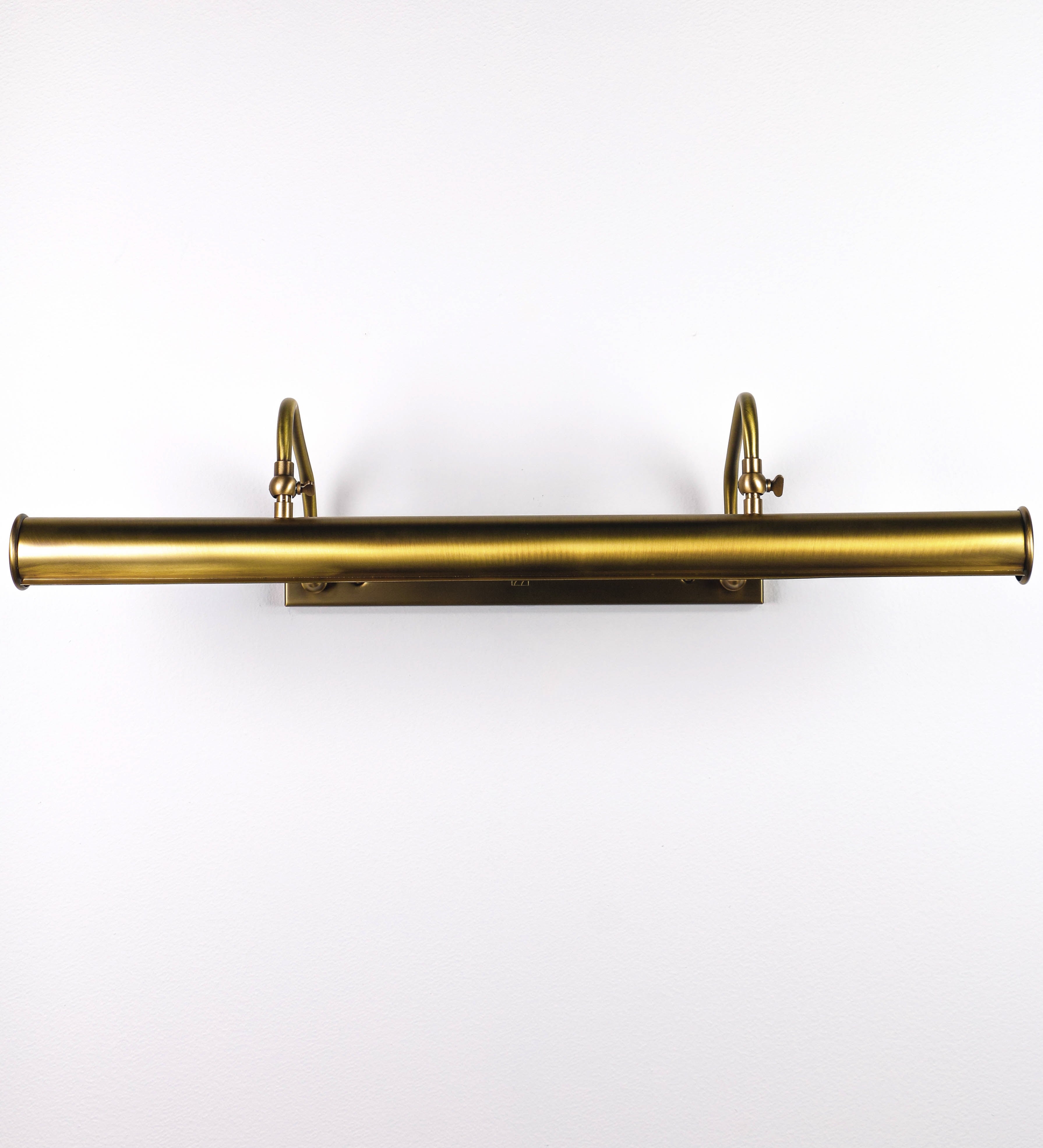 Aplique de parede que combina elementos clássicos com toques contemporâneos, todo em ouro velho. O aplique é composto por uma base retangular, de onde se estendem dois braços curvos e graciosos, que suportam a barra principal. Os braços contêm um elemento que permite apertar ou desapertar a barra para melhor manipular a direção da luz. A barra de 65cm de largura é cilíndrica e alongada. As extremidades do cilindro são planas e do mesmo diâmetro.