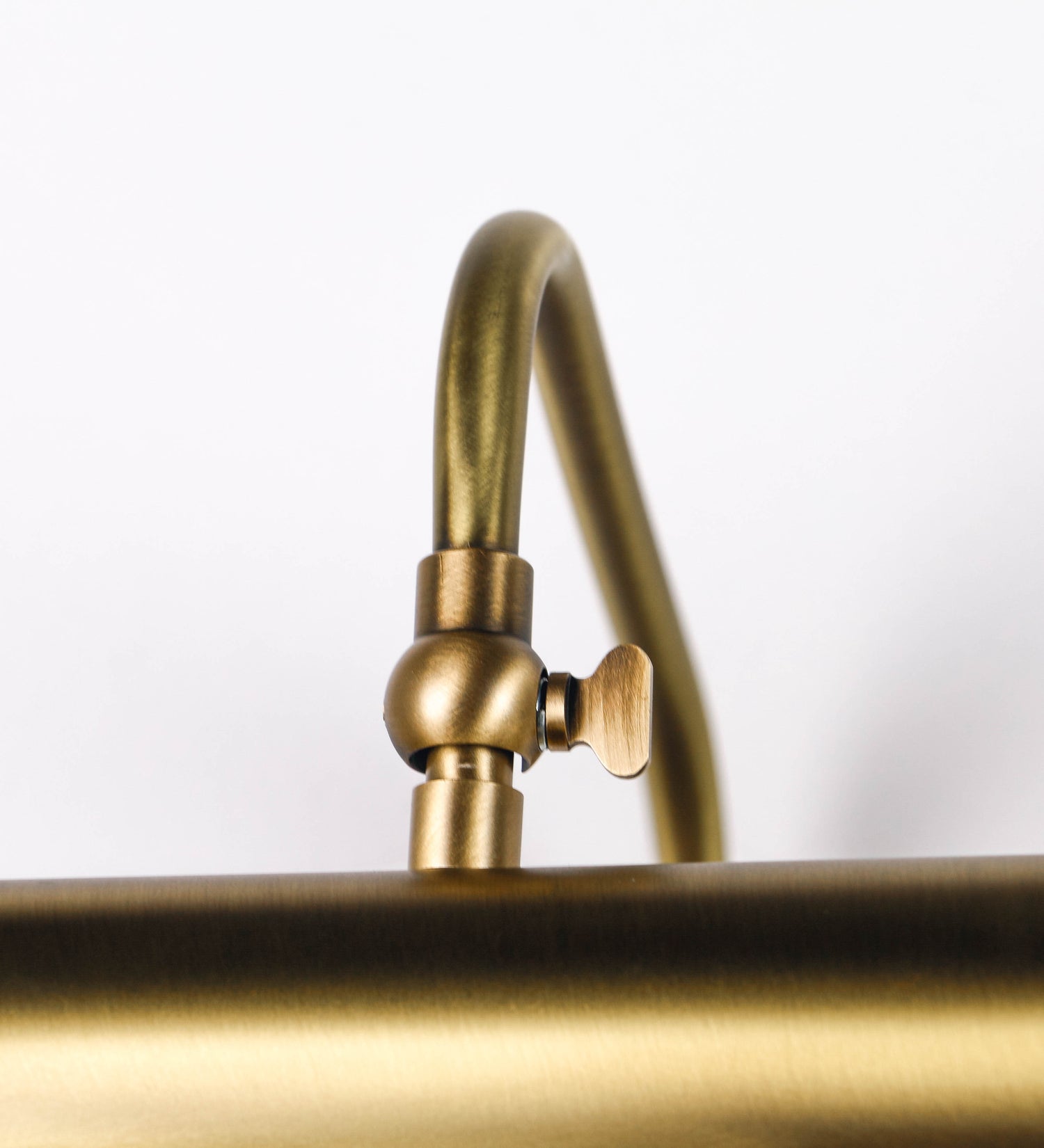 Aplique de parede que combina elementos clássicos com toques contemporâneos, todo em ouro velho. O aplique é composto por uma base retangular, de onde se estendem dois braços curvos e graciosos, que suportam a barra principal. Os braços contêm um elemento que permite apertar ou desapertar a barra para melhor manipular a direção da luz. A barra de 65cm de largura é cilíndrica e alongada. As extremidades do cilindro são planas e do mesmo diâmetro.
