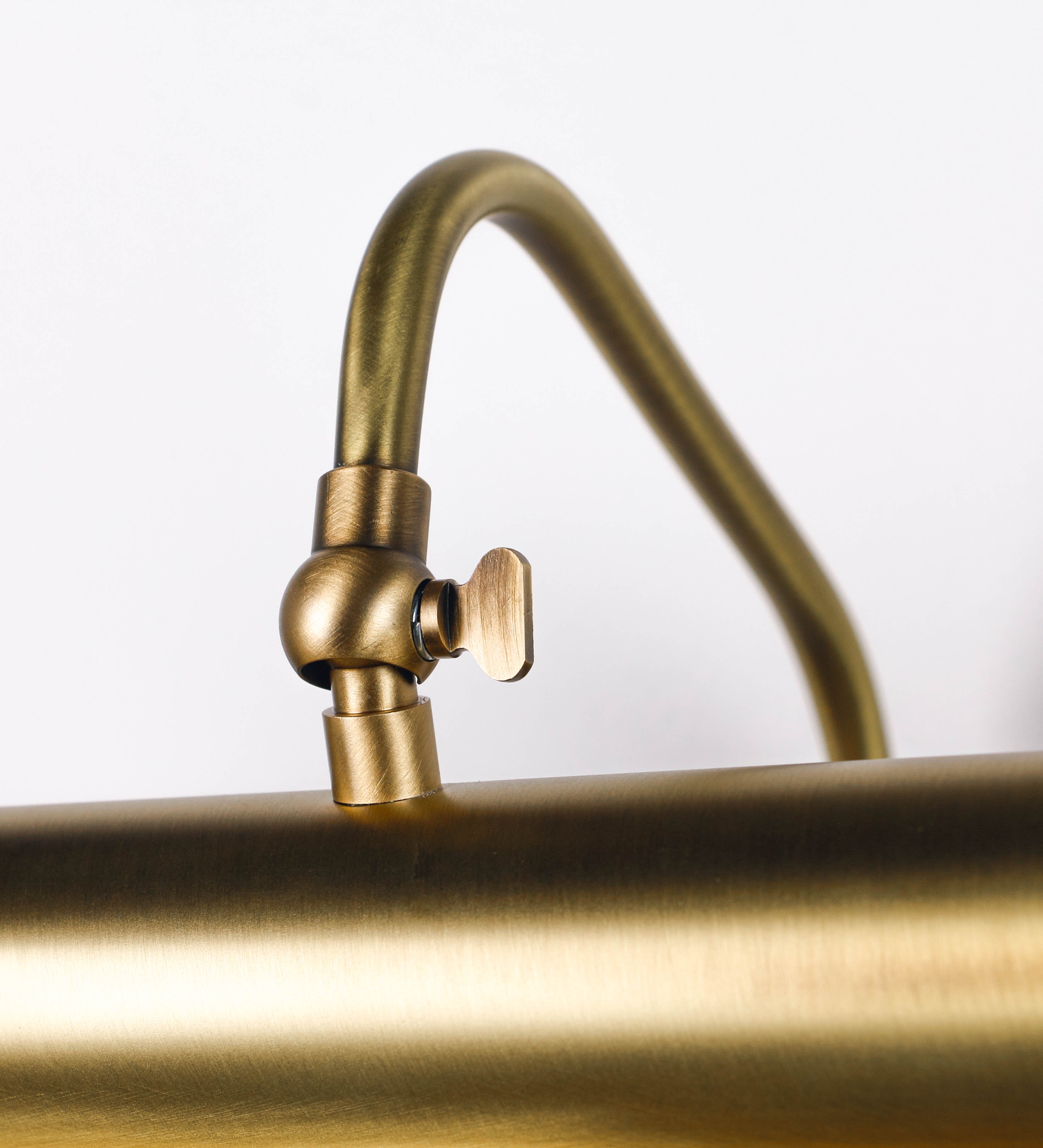Aplique de parede que combina elementos clássicos com toques contemporâneos, todo em ouro velho. O aplique é composto por uma base retangular, de onde se estendem dois braços curvos e graciosos, que suportam a barra principal. Os braços contêm um elemento que permite apertar ou desapertar a barra para melhor manipular a direção da luz. A barra de 65cm de largura é cilíndrica e alongada. As extremidades do cilindro são planas e do mesmo diâmetro.