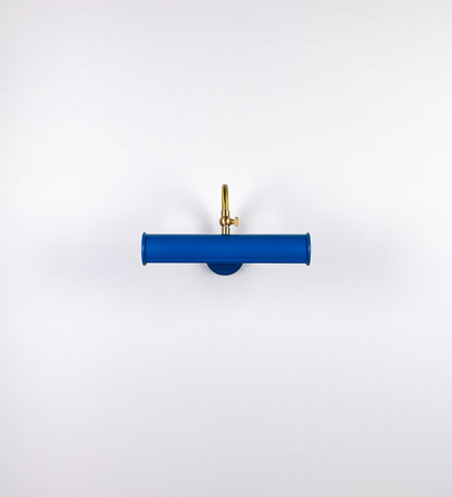 Aplique de parede que combina elementos clássicos com toques contemporâneos. O aplique é composto por uma base circular azul vintage de onde se estende um braço curvo e gracioso, em latão escovado, que suporta a barra principal. O braço contém um elemento, em latão escovado, que permite apertar ou desapertar a barra para melhor manipular a direção da luz. A barra de 25cm de largura, é cilíndrica e alongada, azul vintage. As extremidades do cilindro são planas e do mesmo diâmetro.