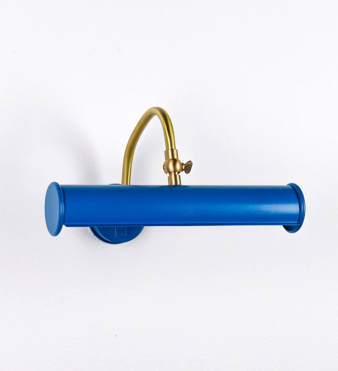 Aplique de parede que combina elementos clássicos com toques contemporâneos. O aplique é composto por uma base circular azul vintage de onde se estende um braço curvo e gracioso, em latão escovado, que suporta a barra principal. O braço contém um elemento, em latão escovado, que permite apertar ou desapertar a barra para melhor manipular a direção da luz. A barra de 25cm de largura, é cilíndrica e alongada, azul vintage. As extremidades do cilindro são planas e do mesmo diâmetro.